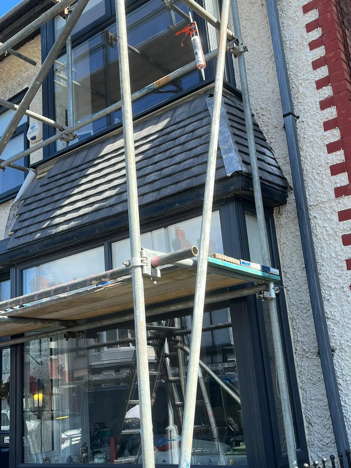 A picture of scaffolding set up for slate roof installation and leadwork on a residential bay window
