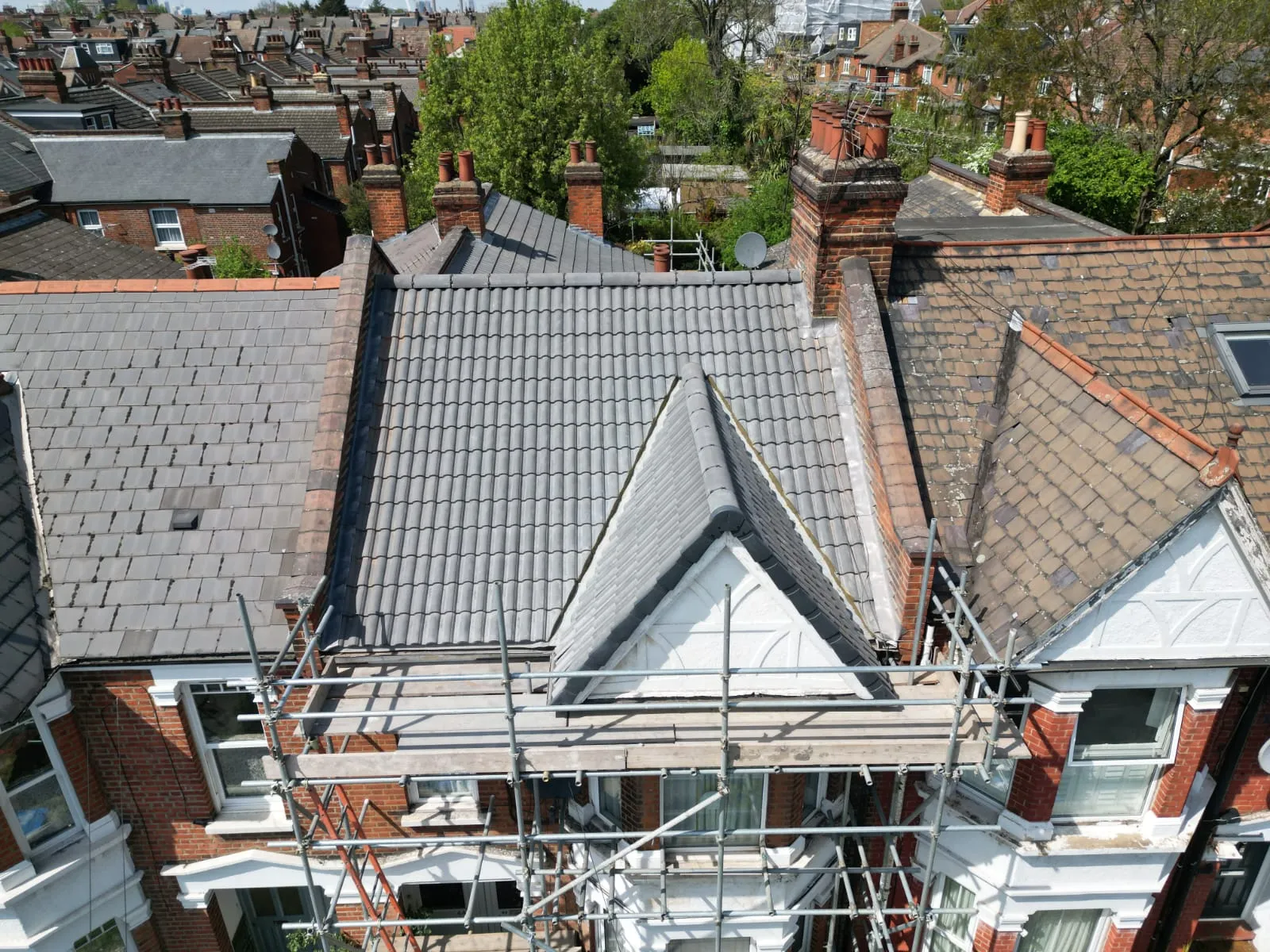 Aerial view of a recently installed grey tiled roof on a residential property, with scaffolding in place.