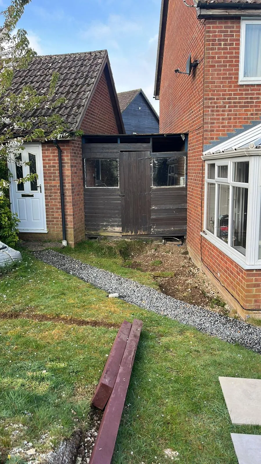 A garden area between two houses with a gravel drainage trench, representing groundwork and site preparation.