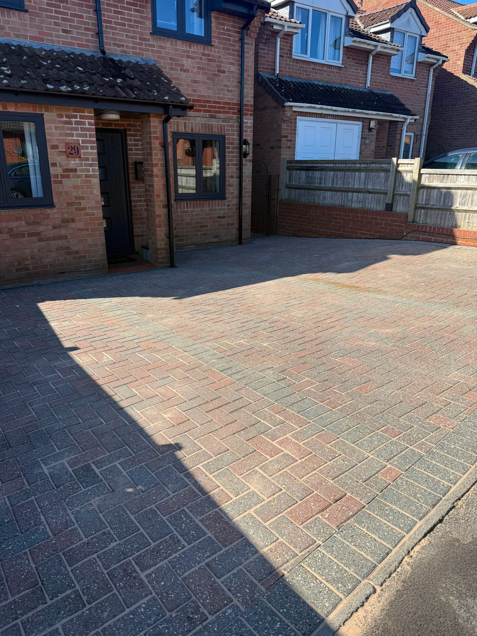 A professionally cleaned and re-sanded block paving driveway outside a brick house, restoring kerb appeal.