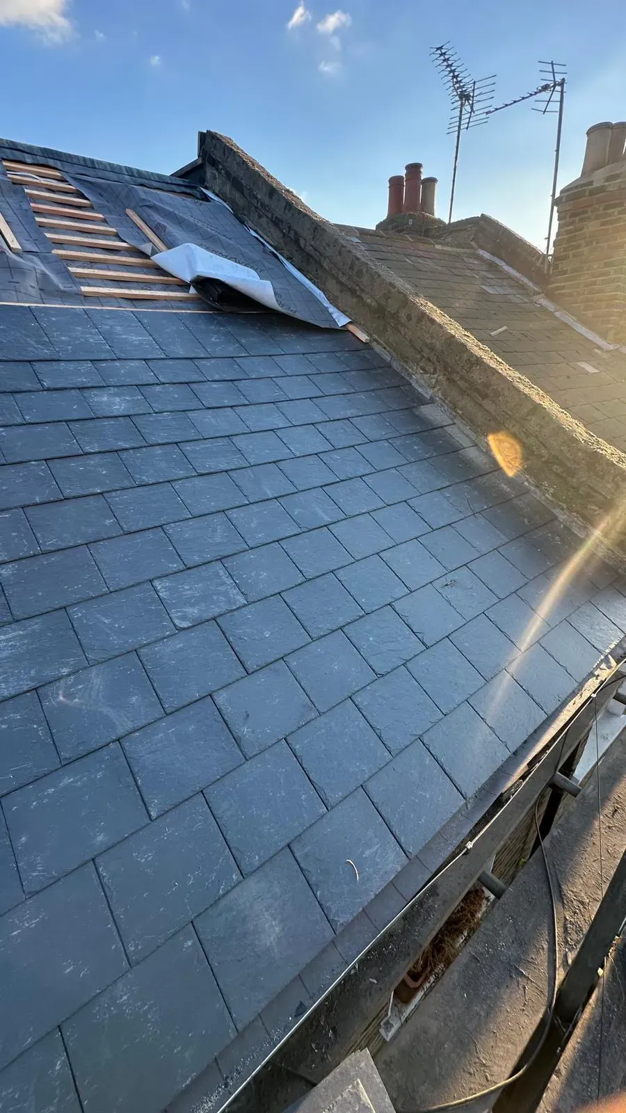Natural slate roof installation and repair on a coastal terraced home showing new slate courses and breathable membrane