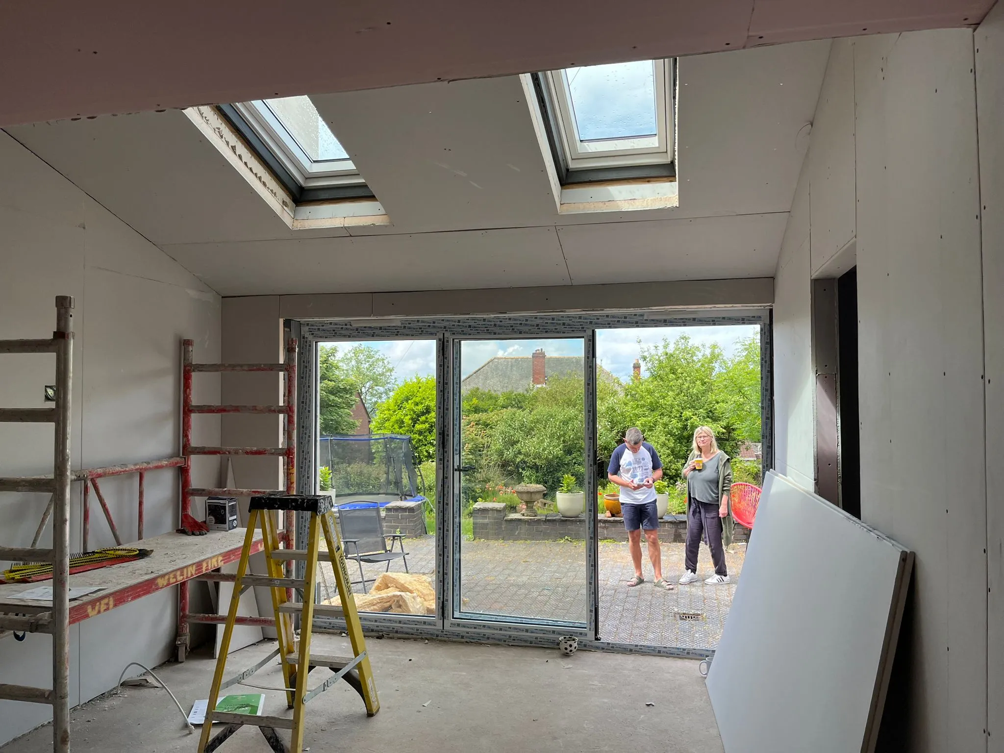 Interior of a home extension with fresh plasterboard, skylights, and bi-fold doors.
