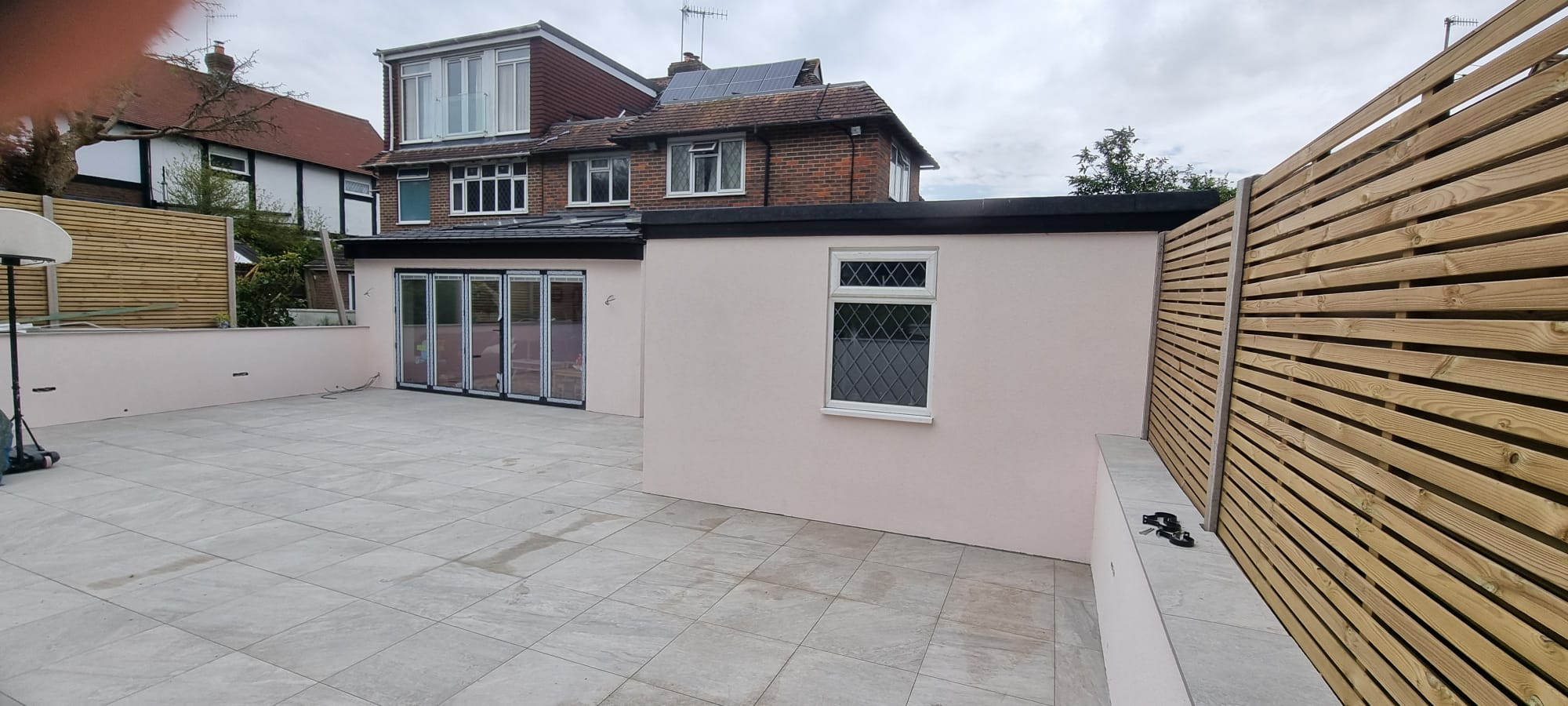 High-quality external rendering on a modern residential extension with bi-fold doors and a paved patio.