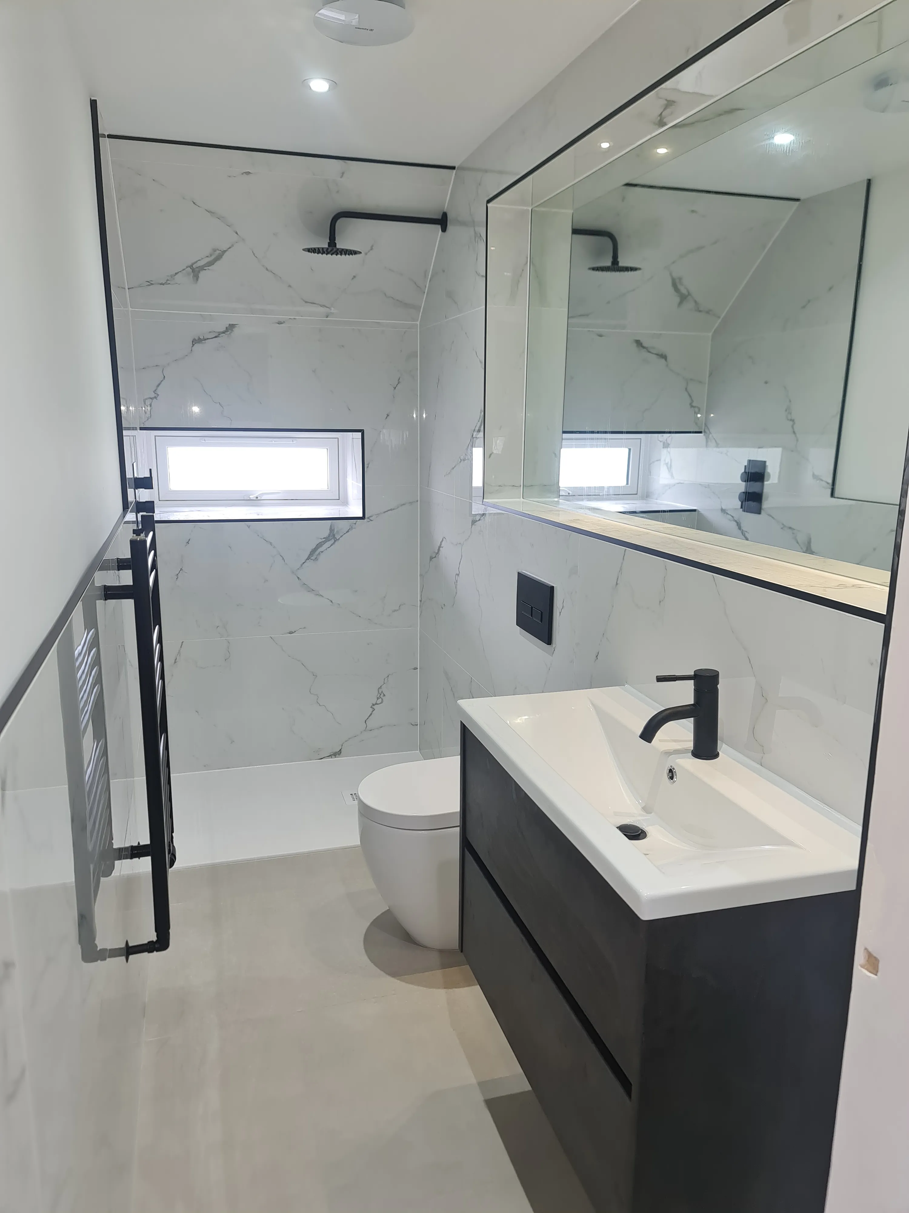 Luxury modern bathroom installation with marble-effect tiling and matte black brassware by Sands & Vossen.