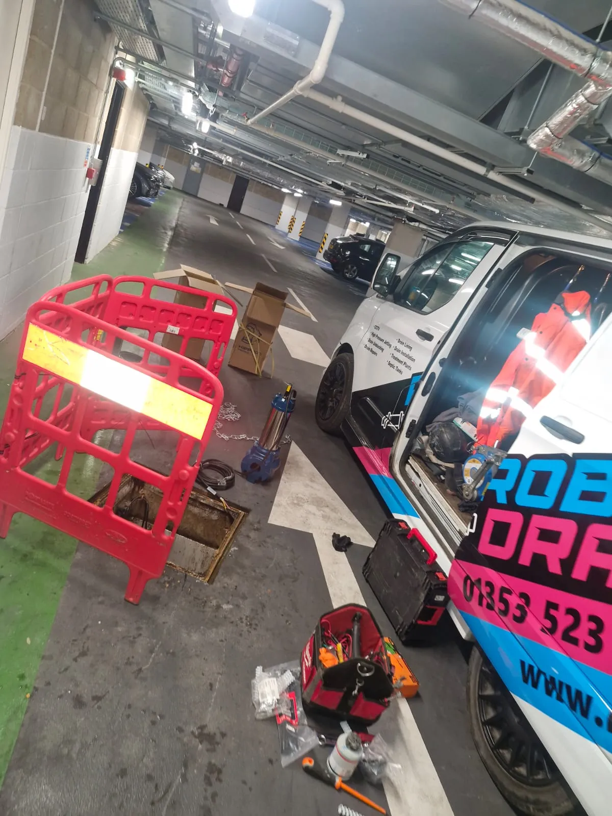 Roberts Drainage Ltd technician performing commercial drainage maintenance and pump servicing in an underground car park.