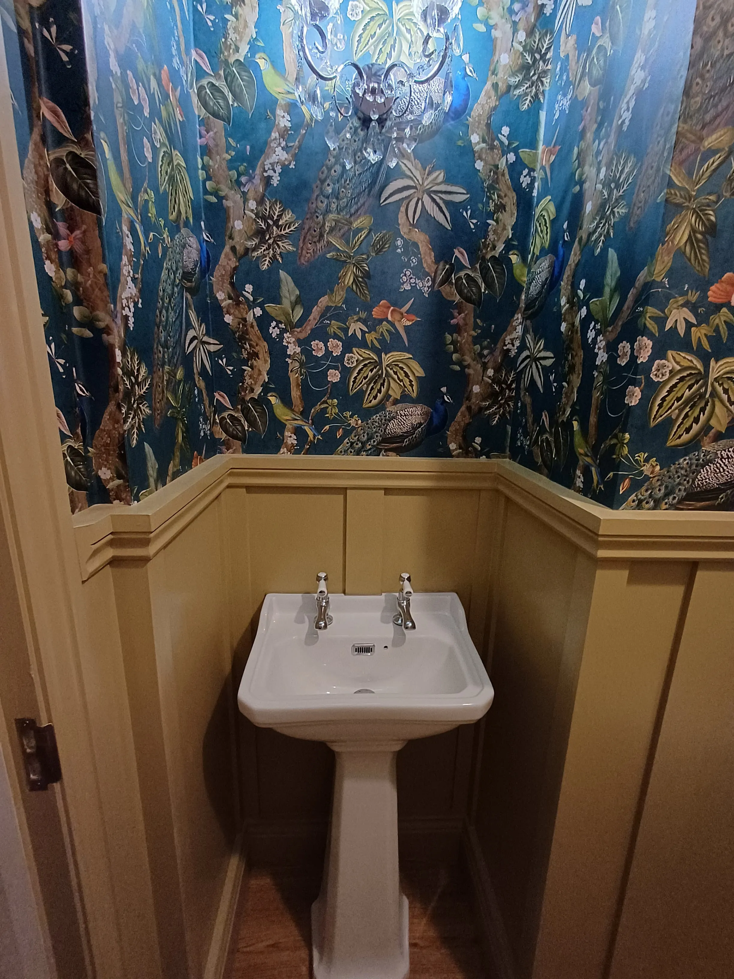 Luxury bespoke cloakroom design in Plymouth featuring maximalist peacock wallpaper and traditional wall panelling by Sands & Vossen.