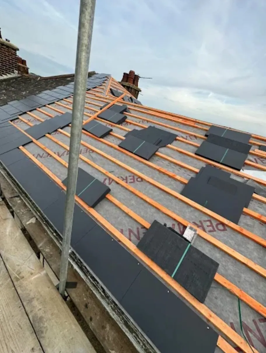 New slate roof installation in progress with timber battens and breathable roofing membrane on a pitched coastal property