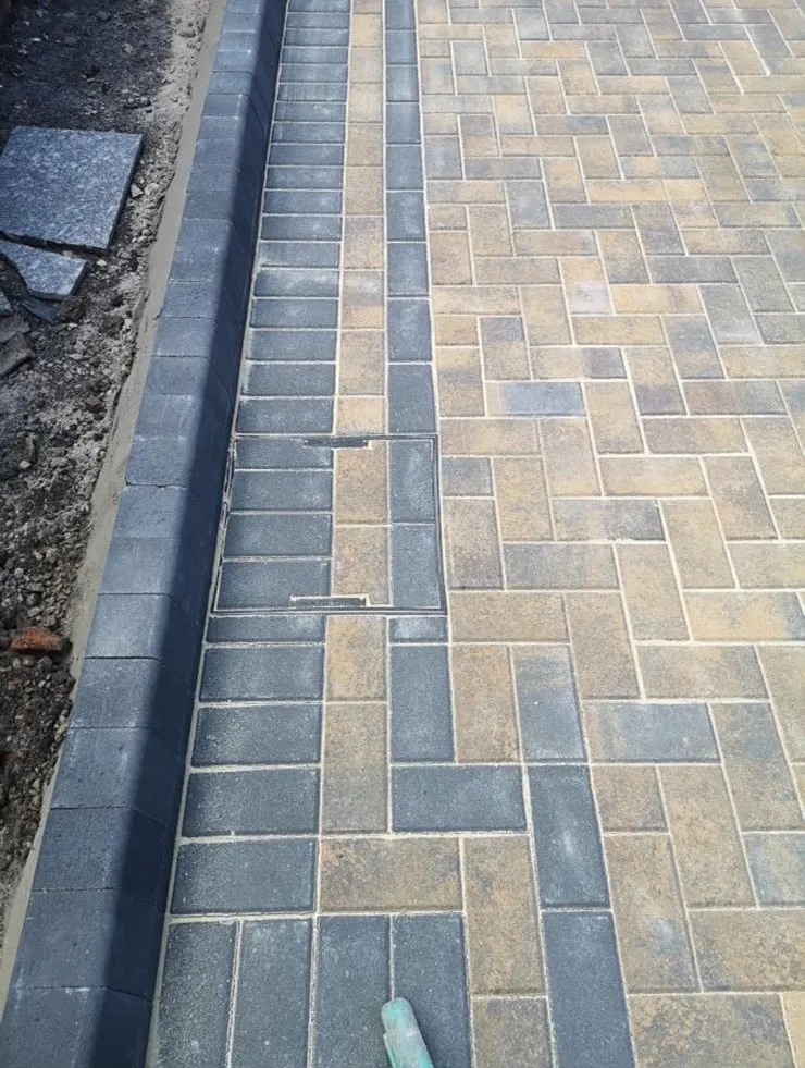 High-quality block paving installation with an integrated recessed manhole cover by Prestige Home Improvements.