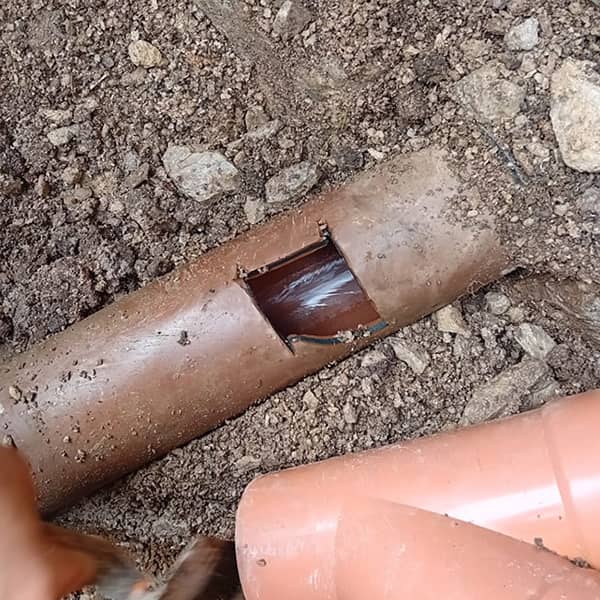 Exposed damaged underground drain pipe undergoing excavation and repair by Drain Medics