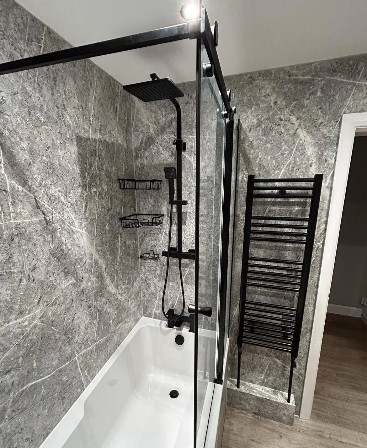 Modern bathroom installation in York with grey marble panels and black fixtures