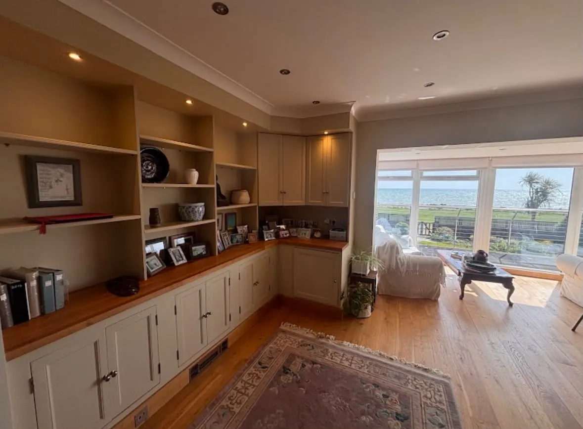 Bespoke feature lighting and ceiling downlights installed in a modern domestic living room with fitted cabinetry