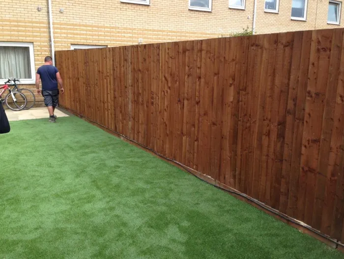 Newly installed wooden garden fence and artificial grass lawn in a residential backyard by Elite Paving and Roofing LTD.