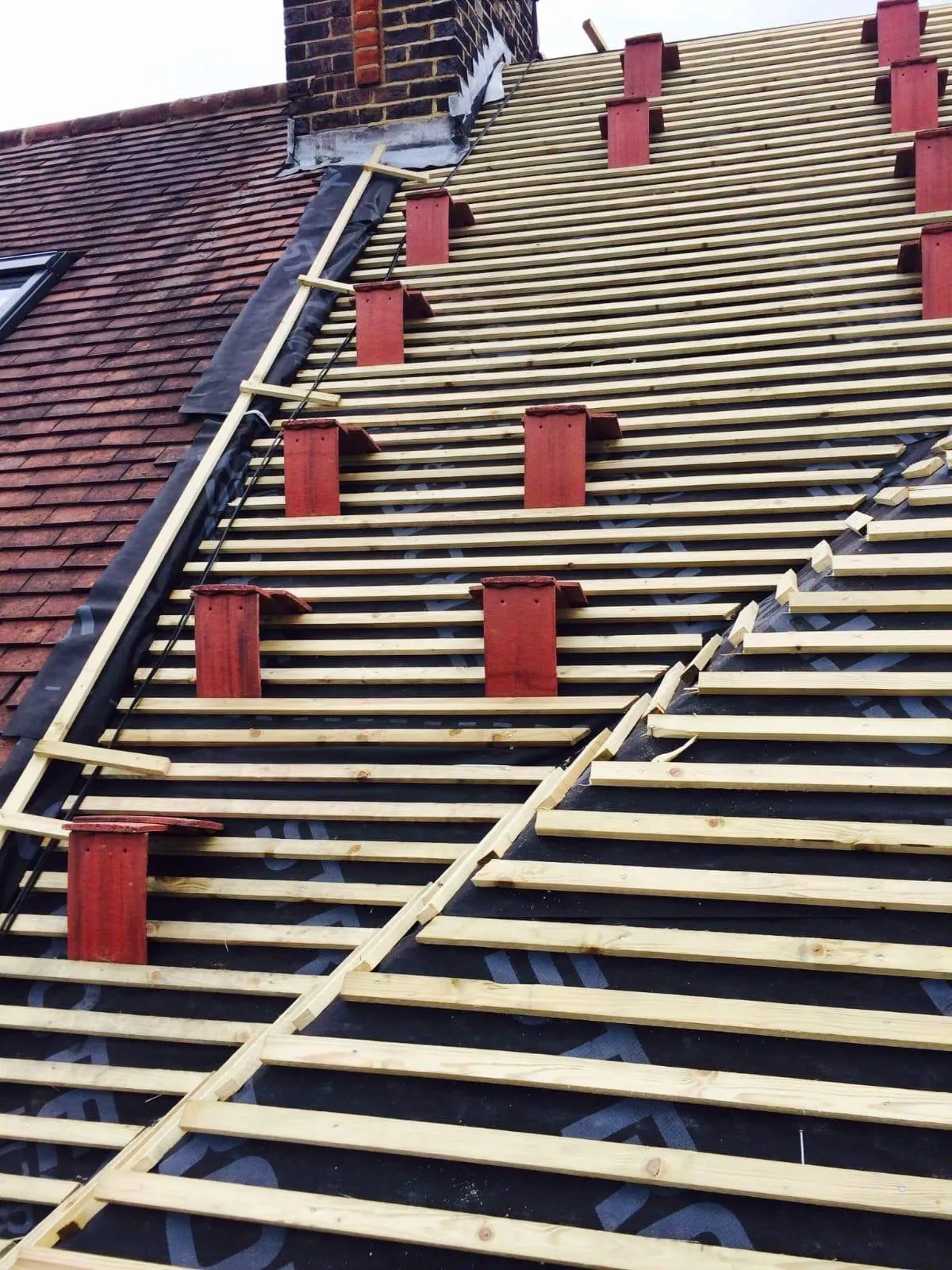 Expert slate and tile roofing installation by Firmus Roofing & Building in Aylesbury showing new battens and tiling process.