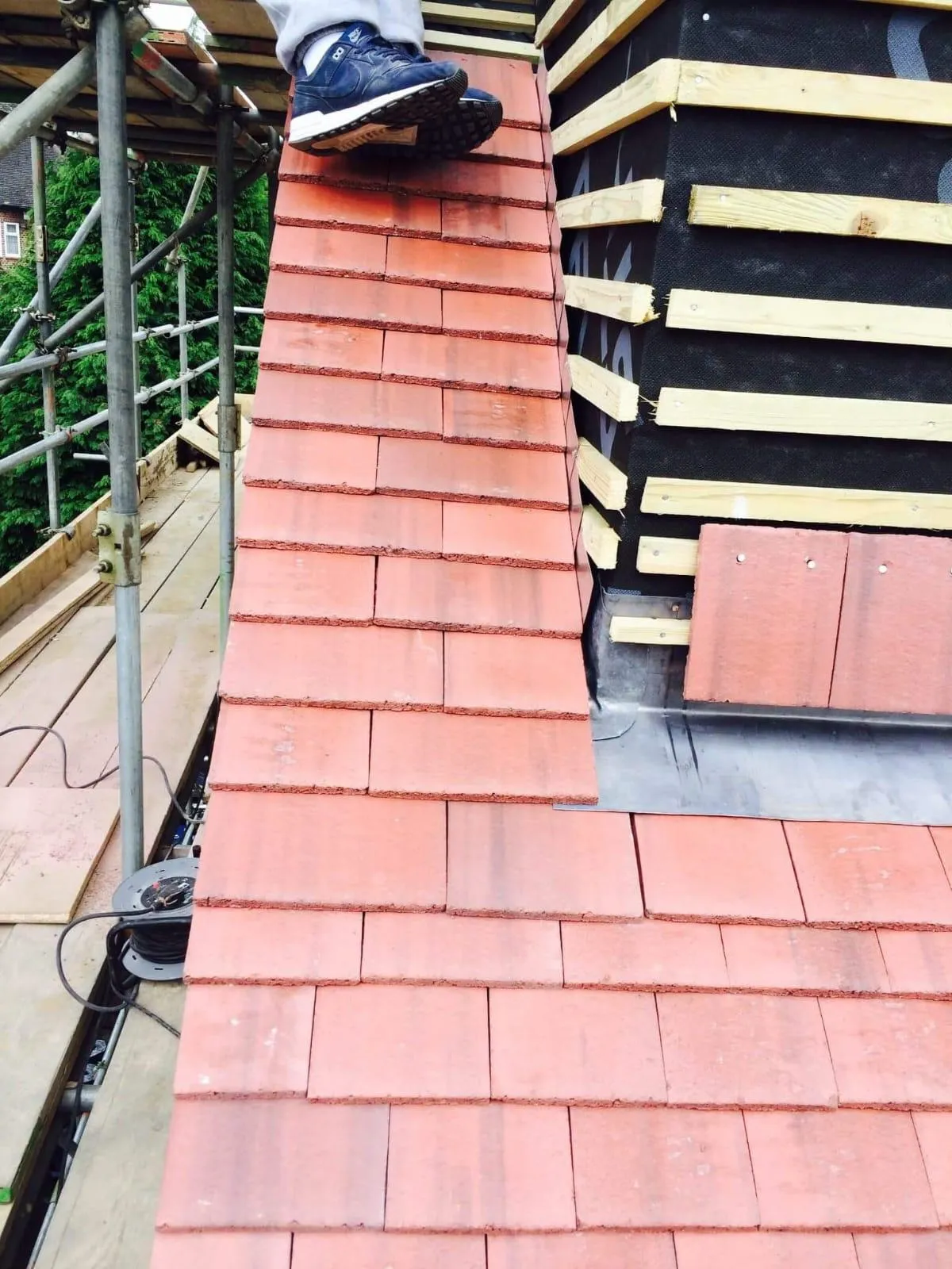 Expert roofers installing red clay tiles and lead flashing on a domestic property in Buckinghamshire.