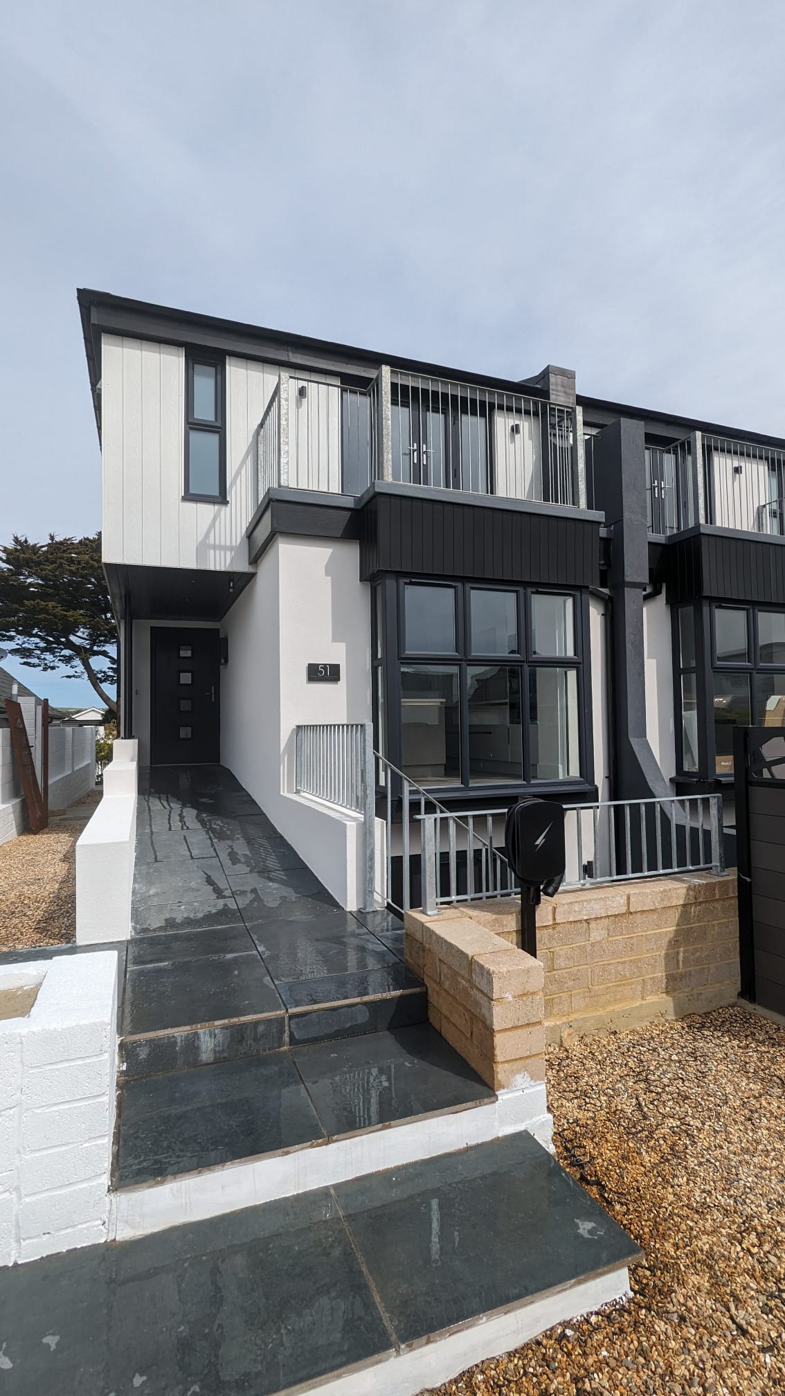Modern house with professionally applied white external rendering and black window frames by Portslade Plastering.
