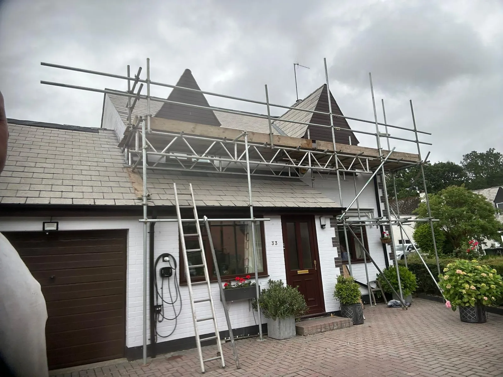 Scaffolding erected for comprehensive roofing work on a white house with grey roof tiles, suggesting a new roof or major repairs in West Berkshire.