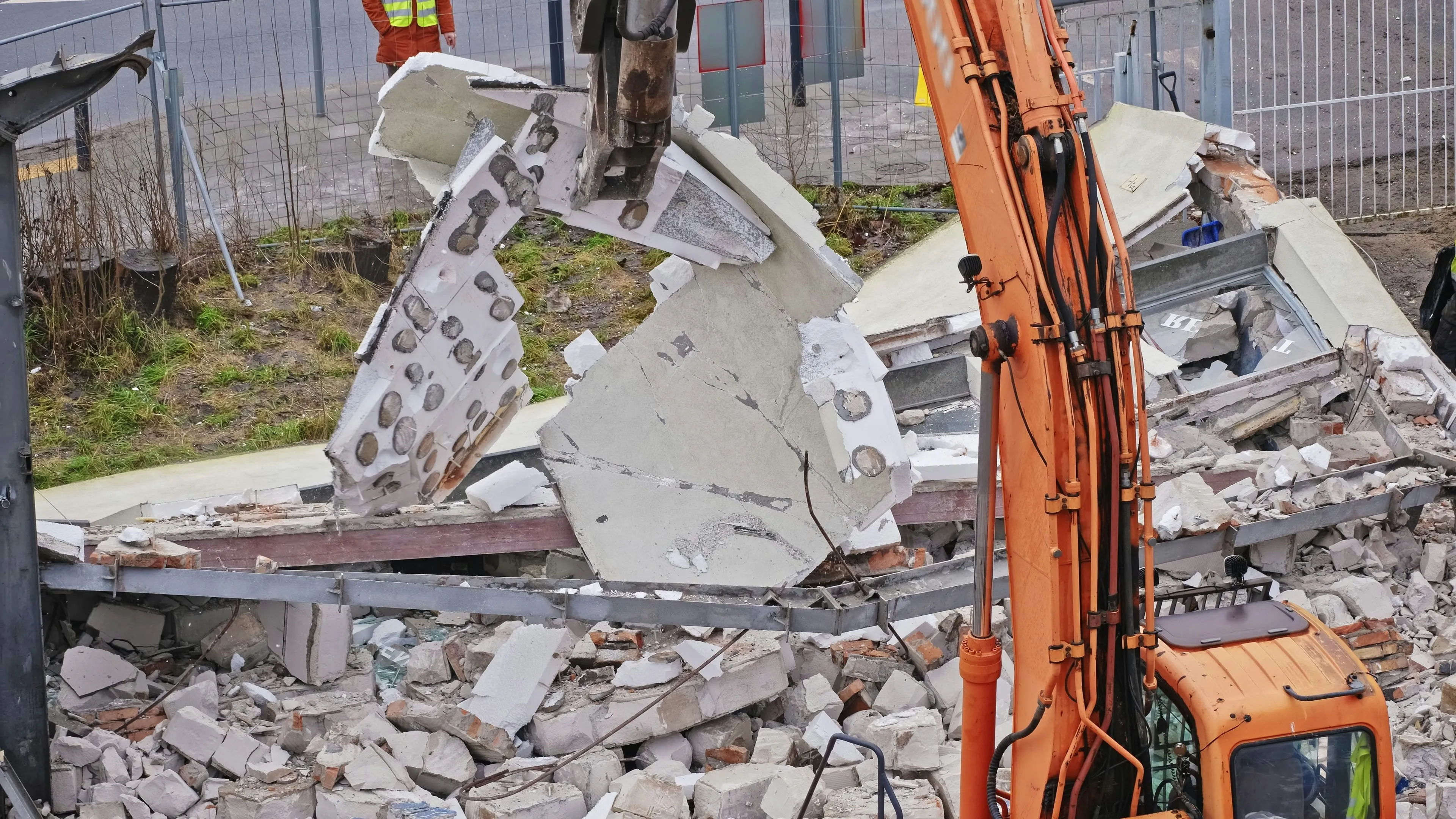 An excavator demolishing a building, indicating large-scale asbestos removal for commercial or industrial properties.