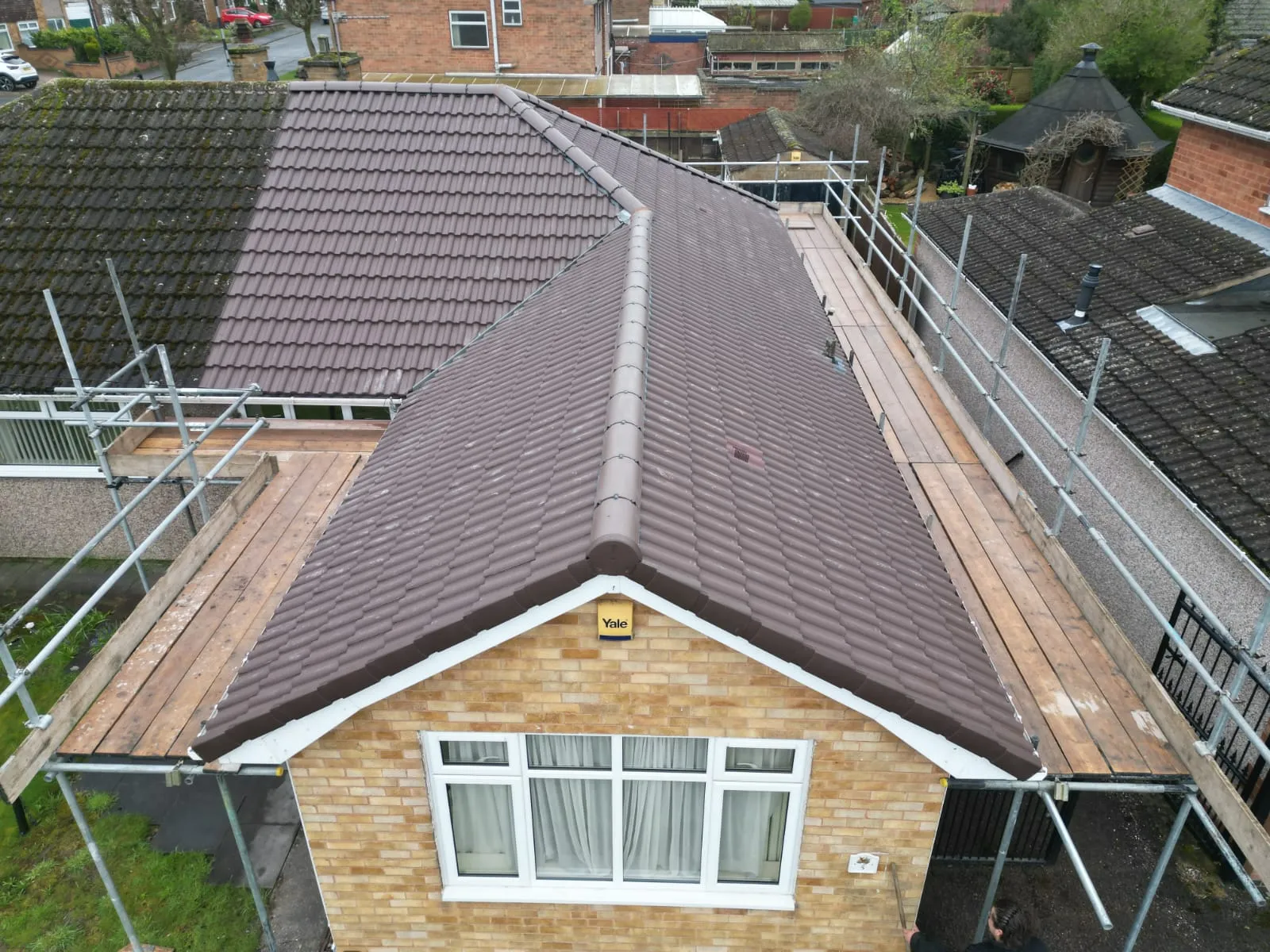 Newly installed brown pitched tiles on a residential roof, with scaffolding, during a re-roofing project by Rooflex Roofing Solutions.