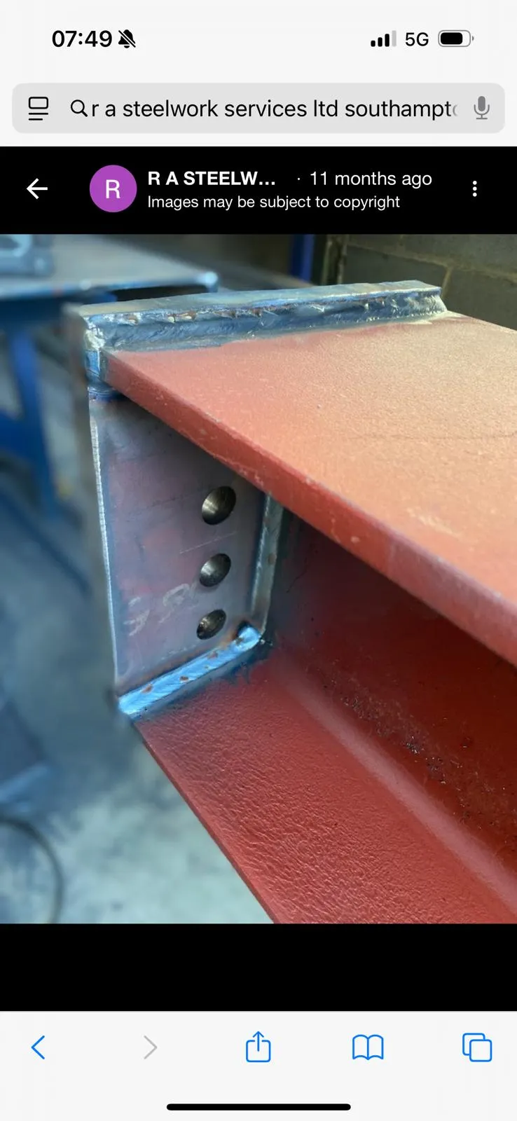 Fabricated red-primed structural steel beam with welded connection plate and bolt holes for a construction project.