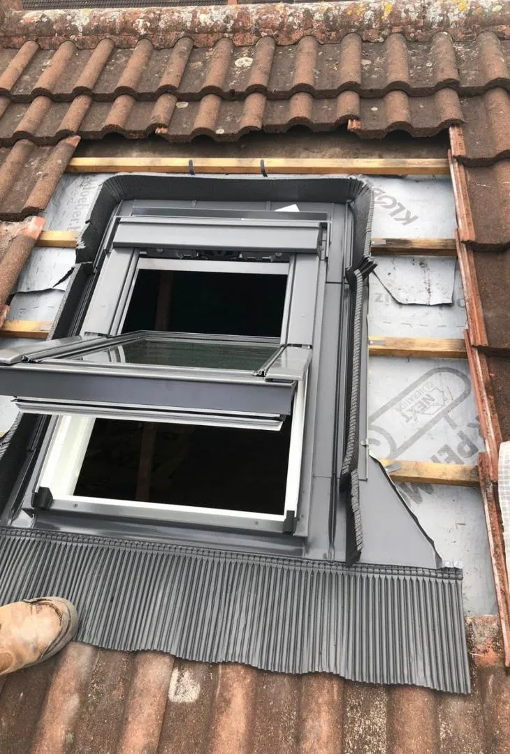 Installation of a Velux roof window on a tiled roof, with flashing and underlay visible.