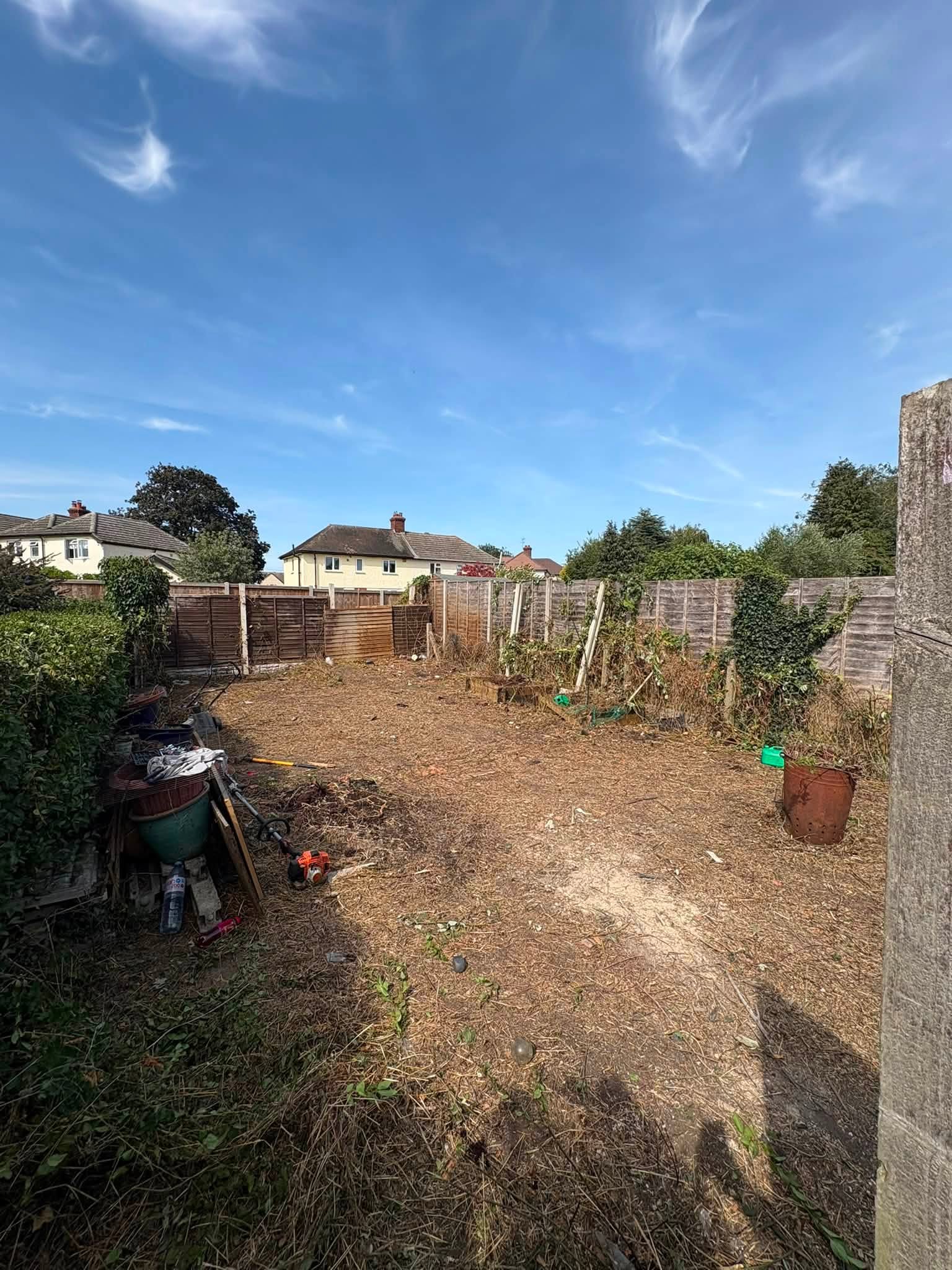 A garden clearance project in progress, showing bare earth and a wooden fence.