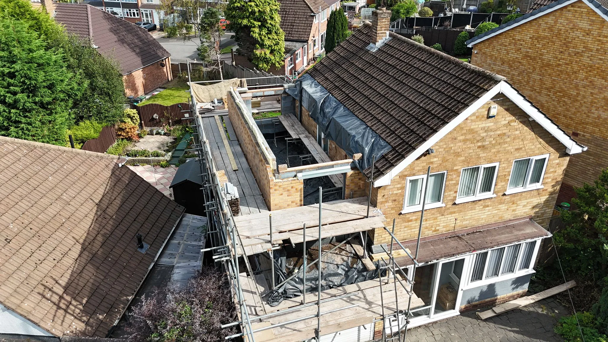 Aerial view of a home extension under construction, showing scaffolding and new brickwork in progress.