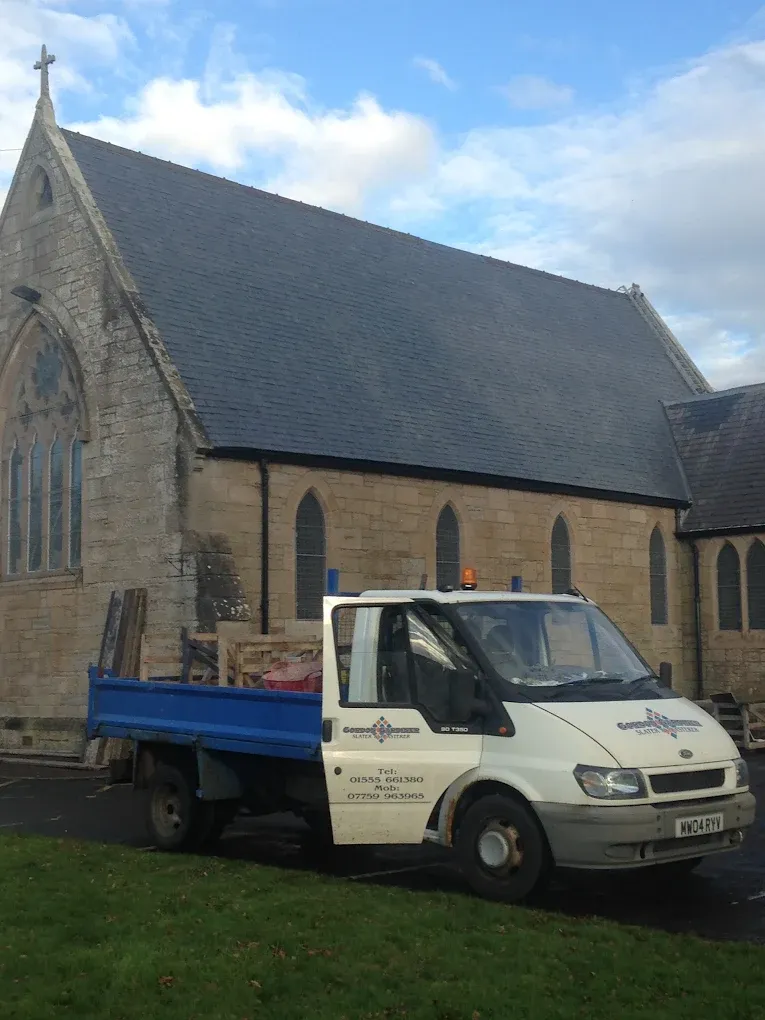 Gordon Gardiner Slater & Plasterer van parked outside a traditional stone church with a slate roof