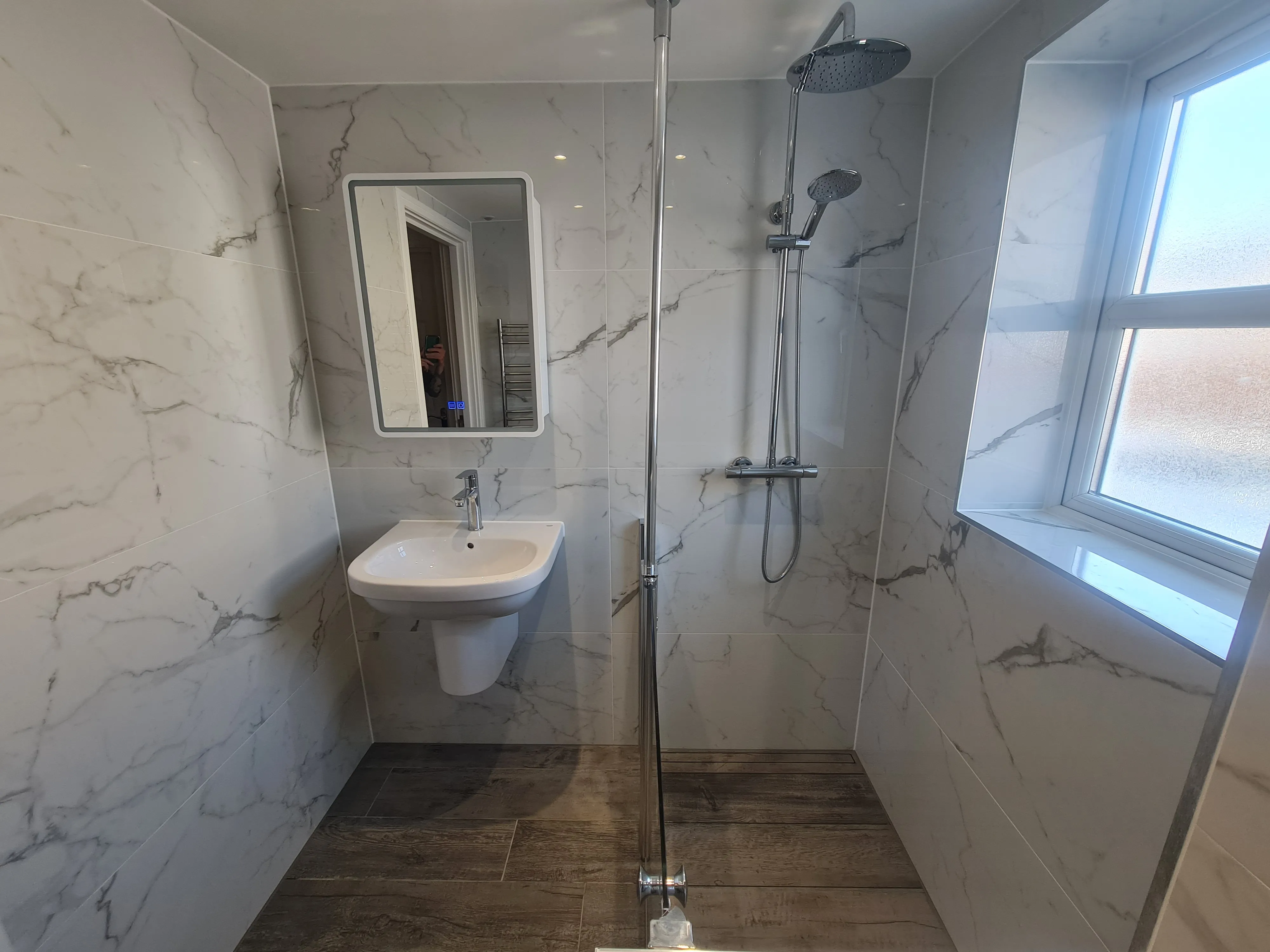 Bespoke luxury walk-in shower installation with marble-effect tiling and chrome fixtures by Sands & Vossen in Plymouth.
