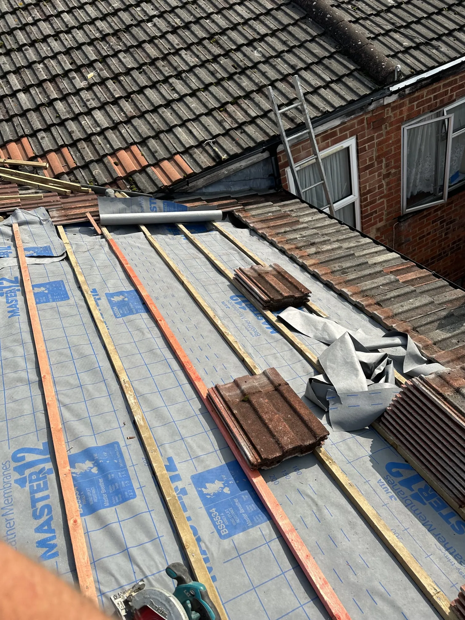A close-up picture of a roof under construction with new wooden battens and breathable membrane.