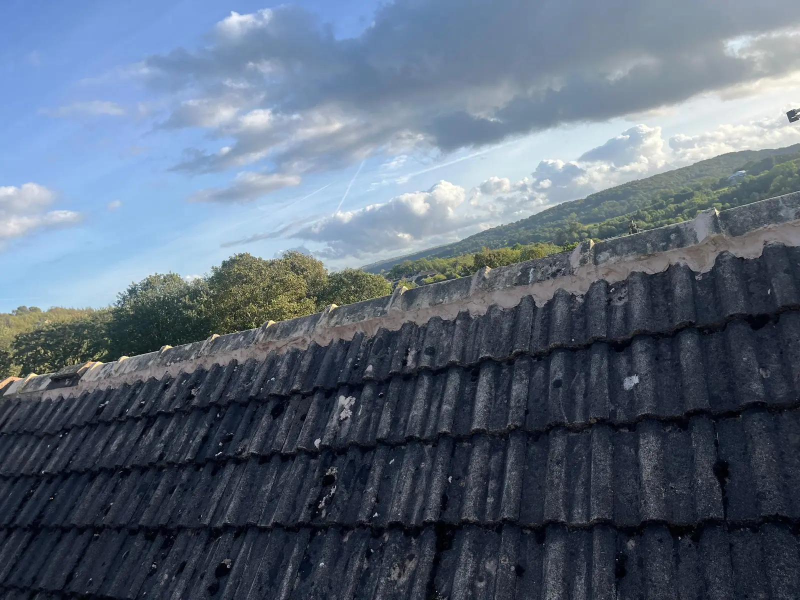 A pitched concrete tile roof with newly pointed mortar along the ridge tiles