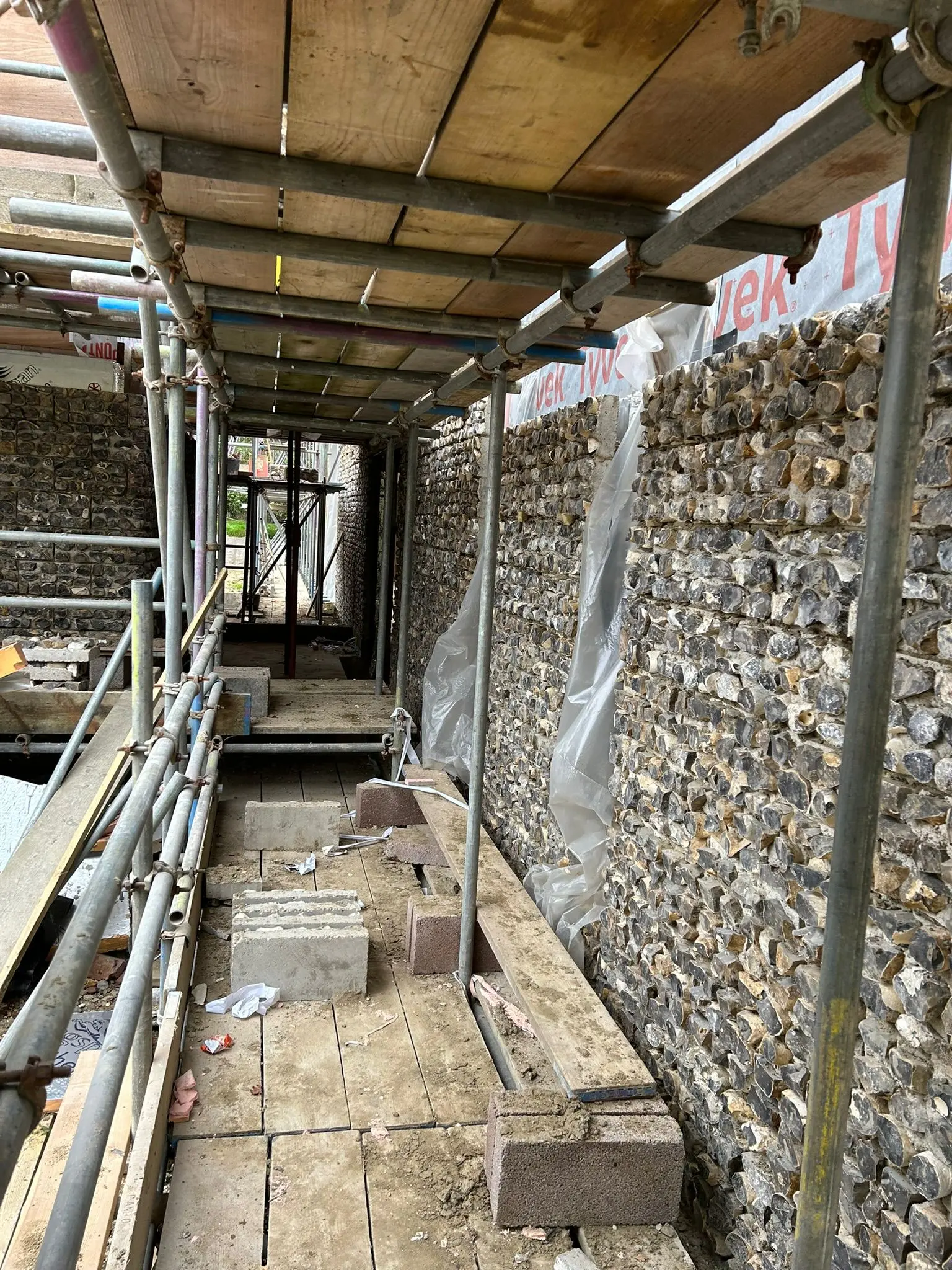 Flint wall masonry and scaffolding on a construction site