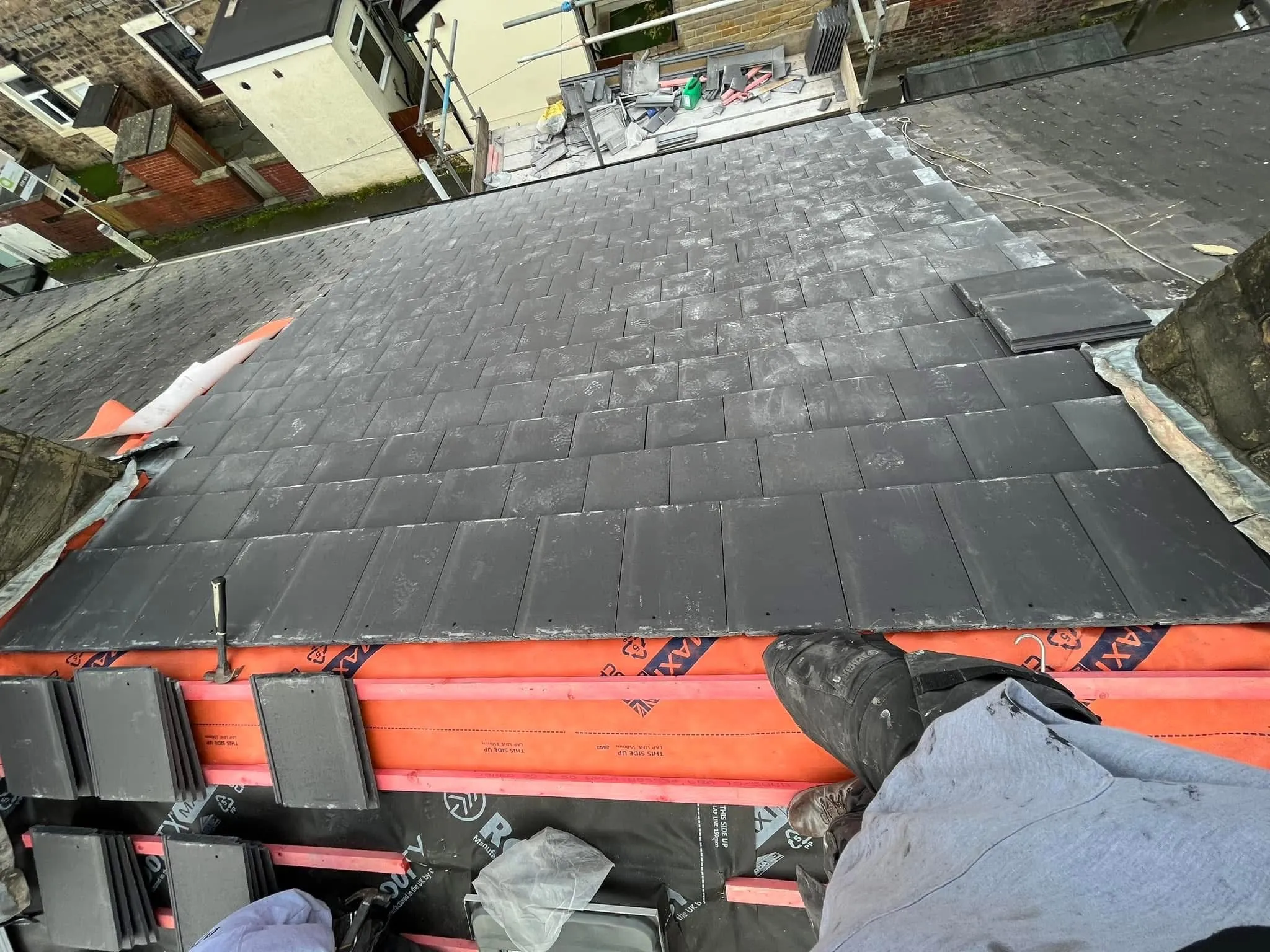 Expert roofer installing a new slate and tile roof in Blackburn, Lancashire, showing the orange membrane and battens.