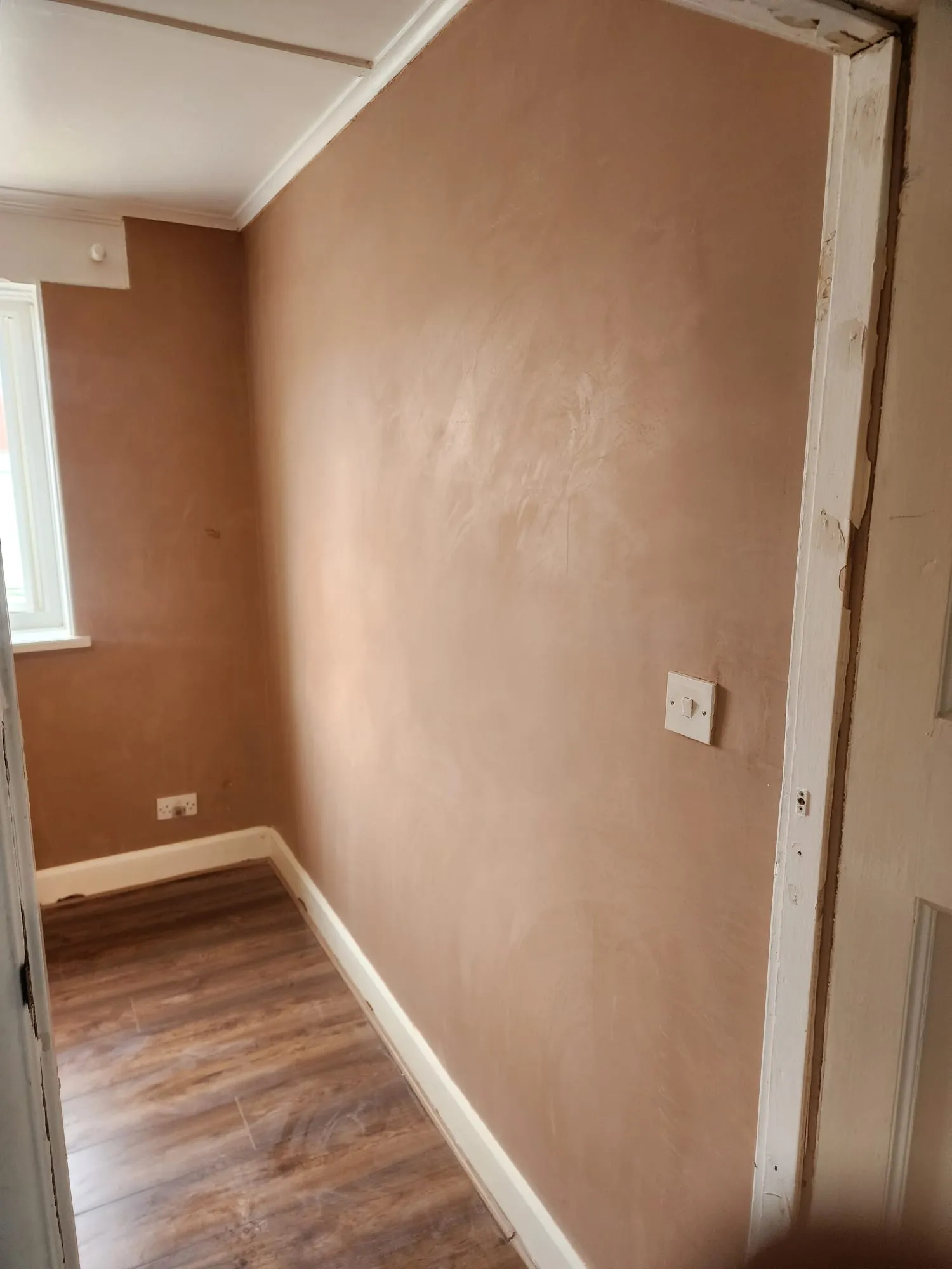 Freshly plastered wall in a residential room showing a smooth, professional finish.