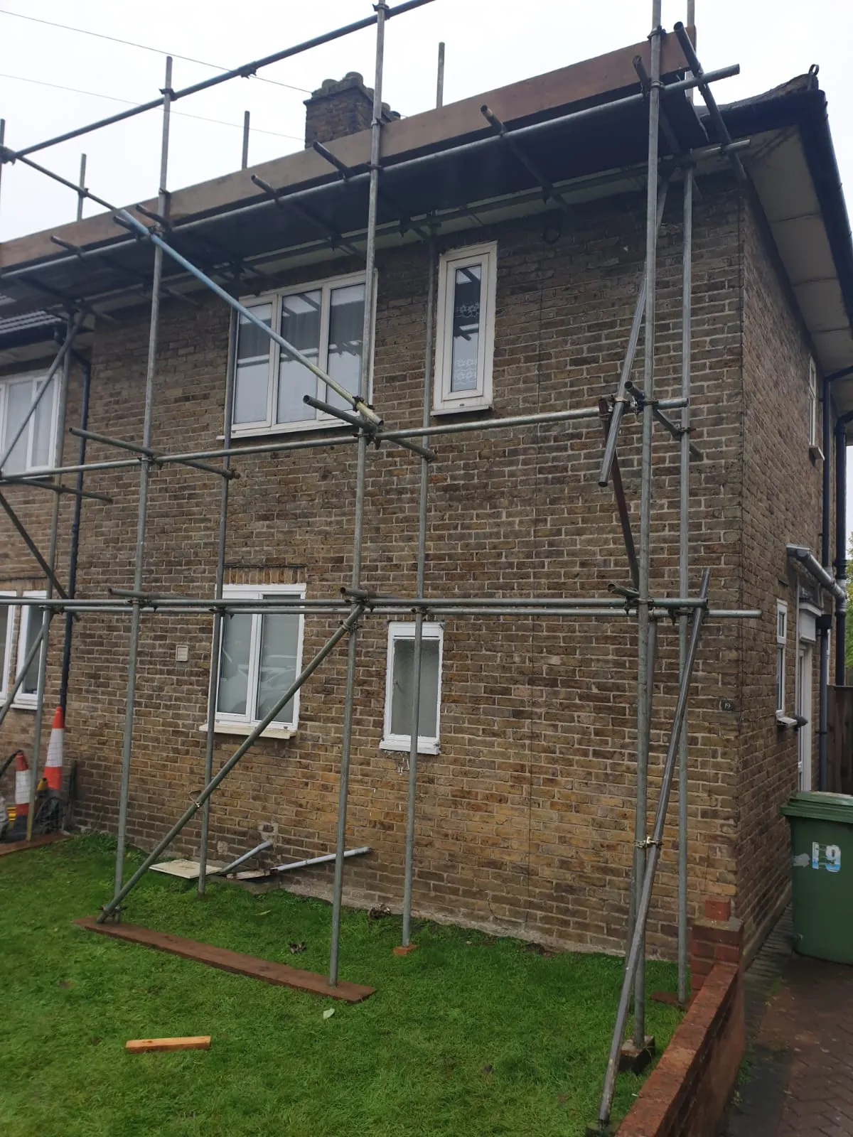 Scaffolding erected around a two-storey brick house for roof replacement or repairs.