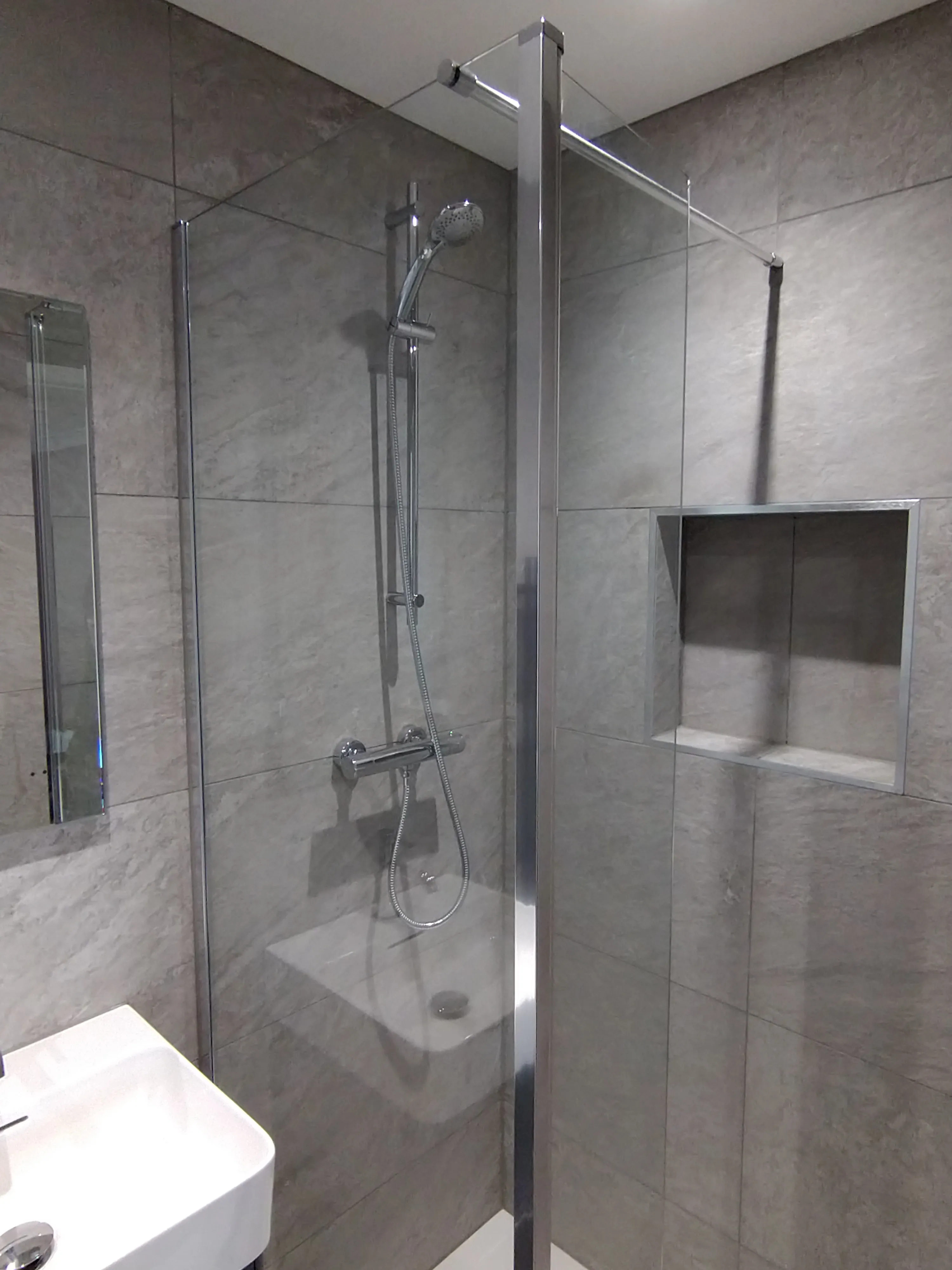 Bespoke luxury walk-in shower installation with grey tiling and chrome hardware by Sands & Vossen in Plymouth.