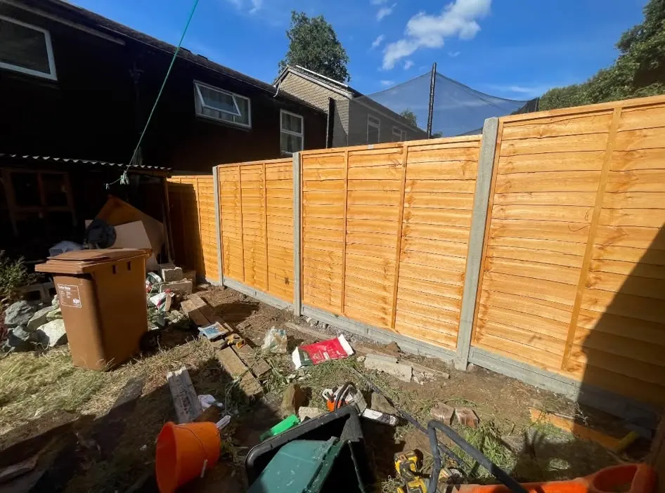 Newly installed wooden garden fence with concrete posts and gravel boards in a residential garden
