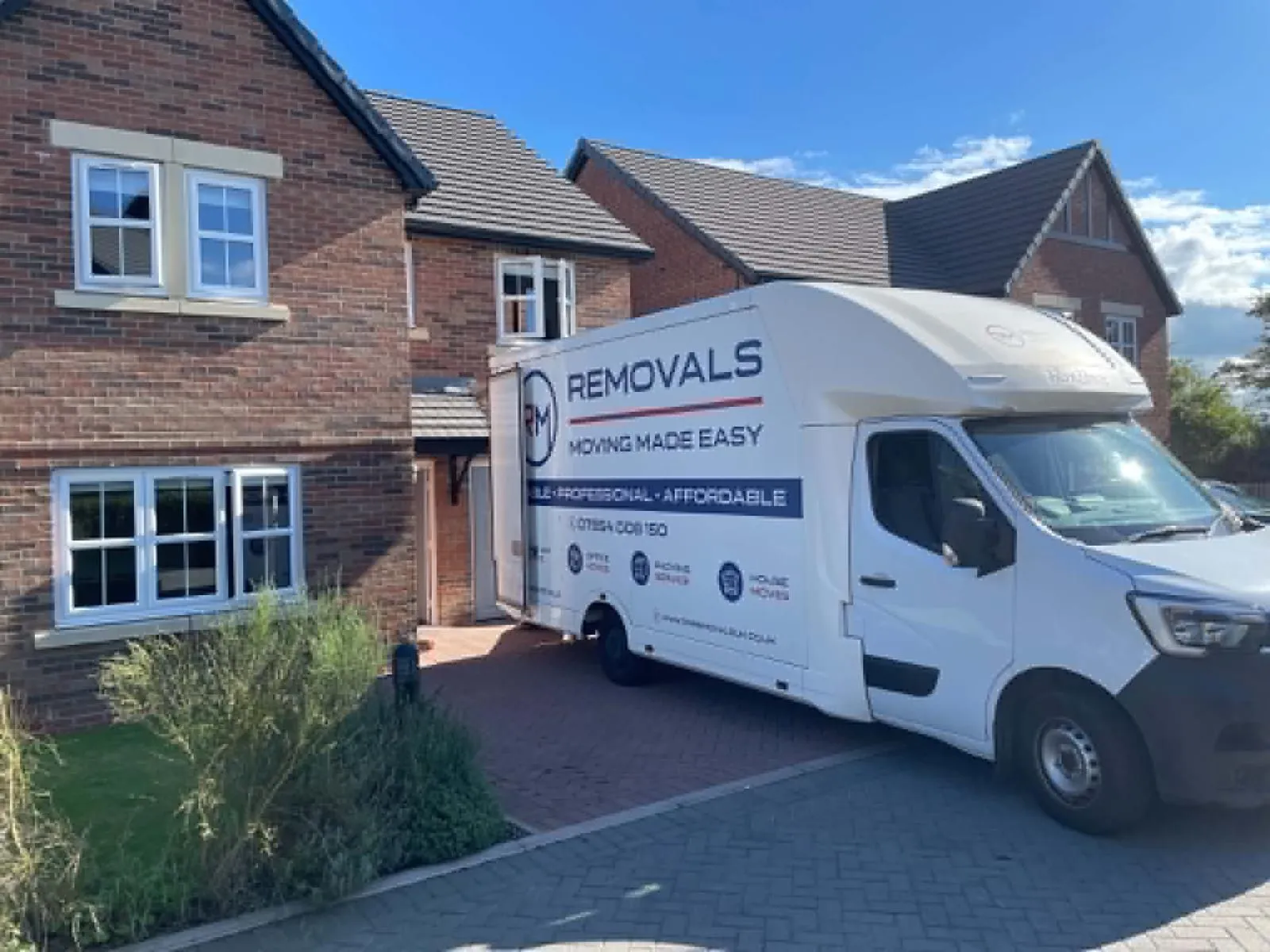 RM Removals van parked on a residential driveway outside a modern home