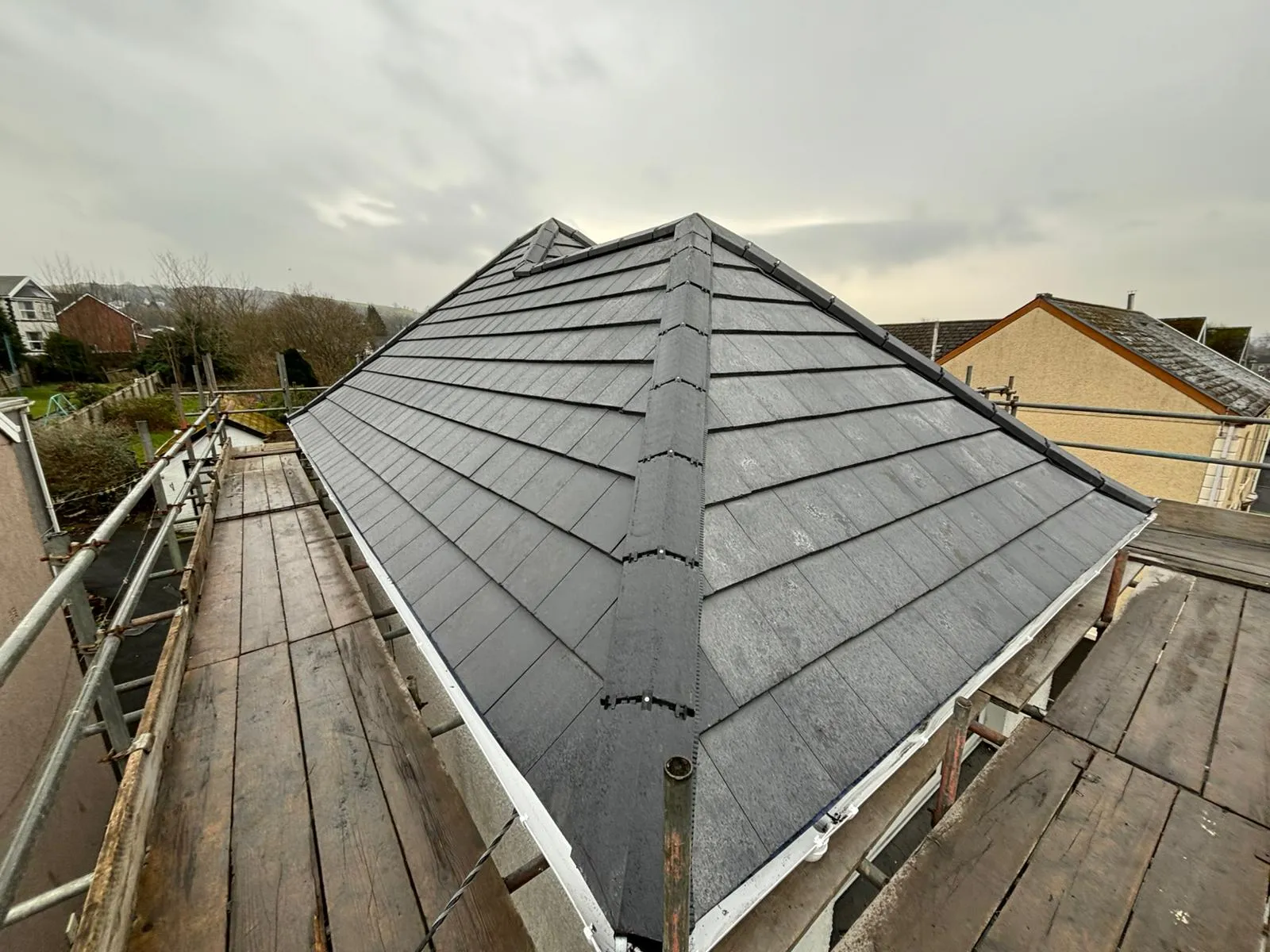 Newly installed slate-effect tiled pitched roof with a dry ridge system on a residential property.