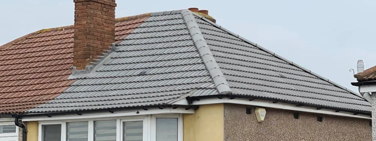 Professional new roof installation featuring grey tiles and new gutters on a residential home.
