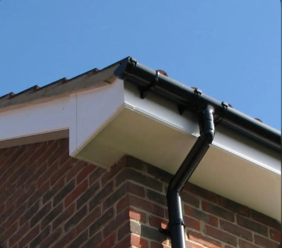 Close-up of black guttering and white fascias and soffits on a house roofline