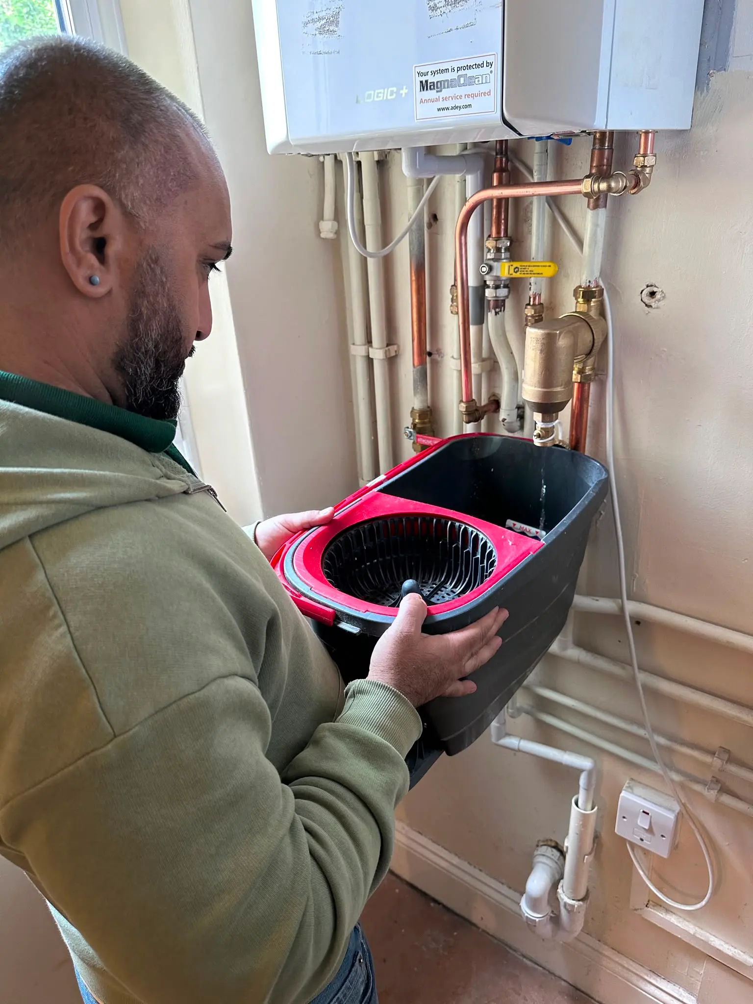 A Gas Safe registered engineer from JMA Plumbing & Heating draining water from a boiler system during a service