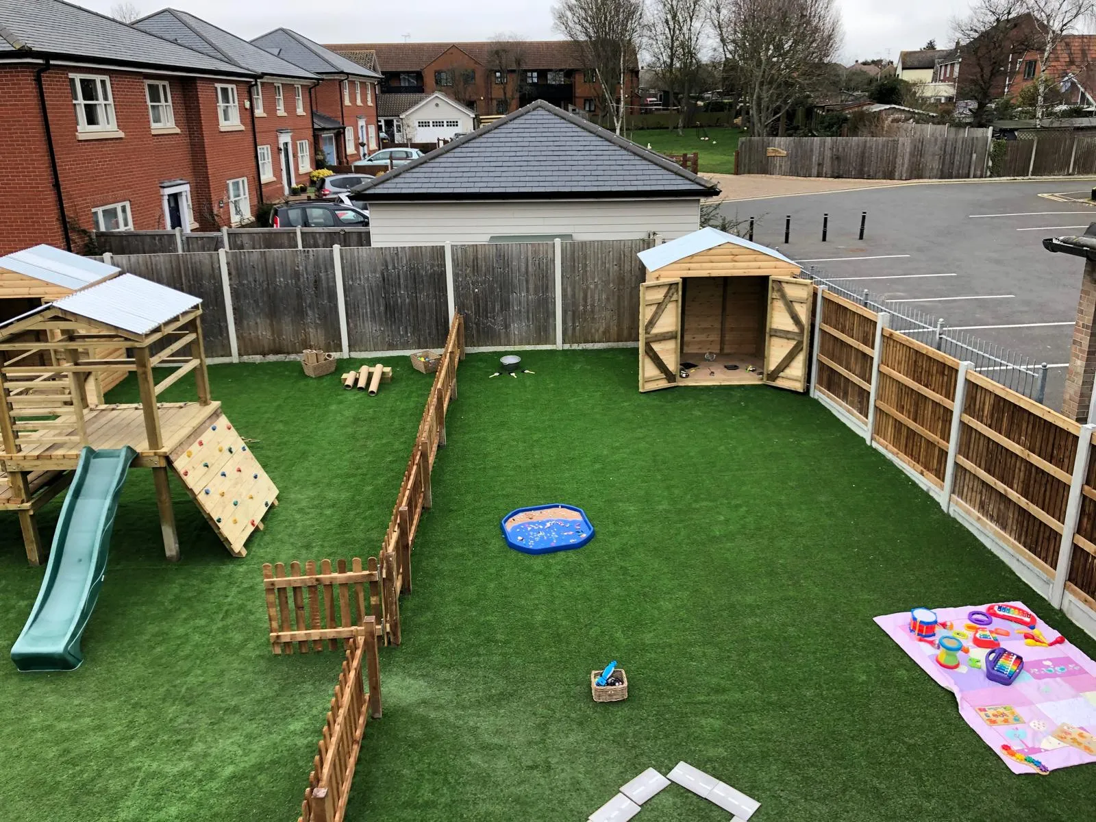 Landscaped garden with artificial grass, timber fencing, children's play area, and wooden shed.