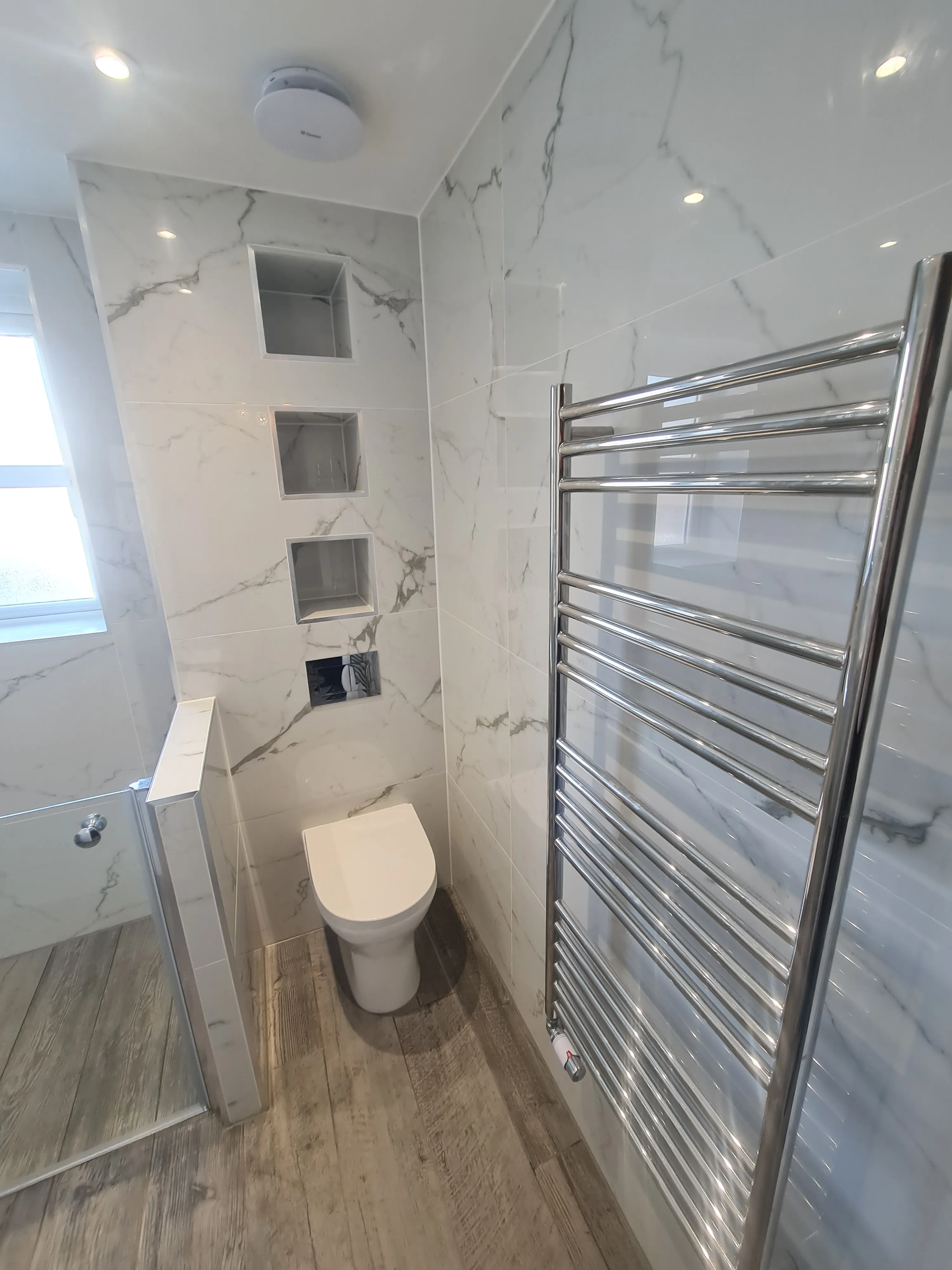 Bespoke luxury bathroom installation in Plymouth featuring marble tiling and recessed shelving by Sands & Vossen.