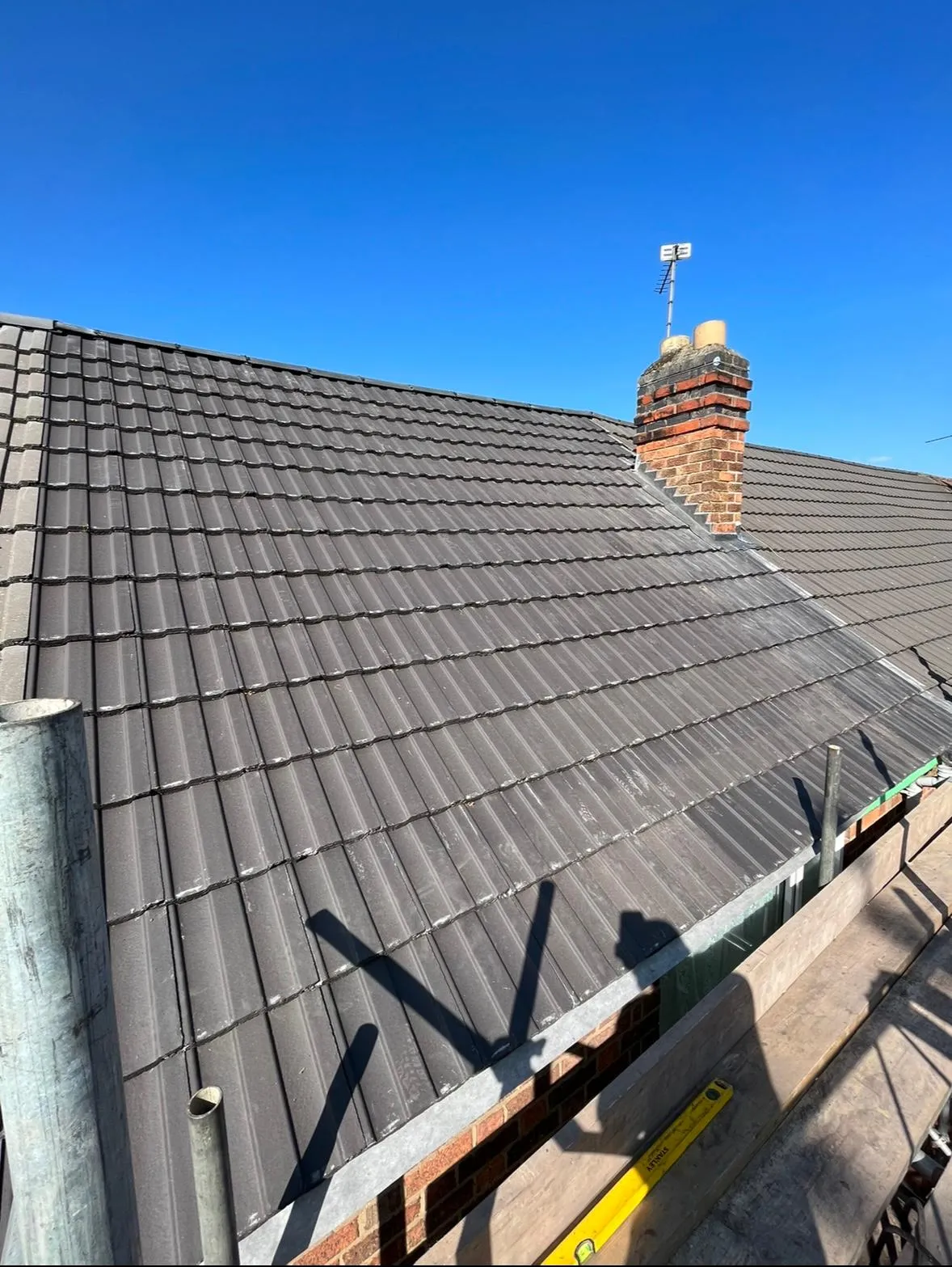 A newly tiled pitched roof with a brick chimney stack