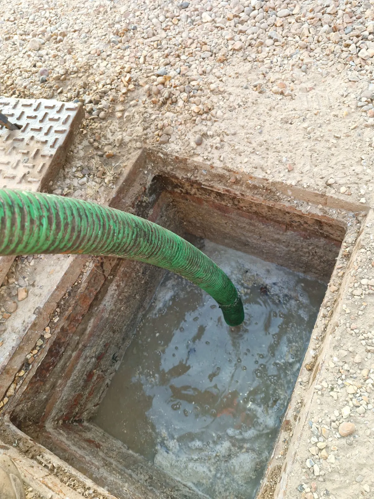 A vacuum tanker hose emptying a septic tank or cesspit by Roberts Drainage Ltd