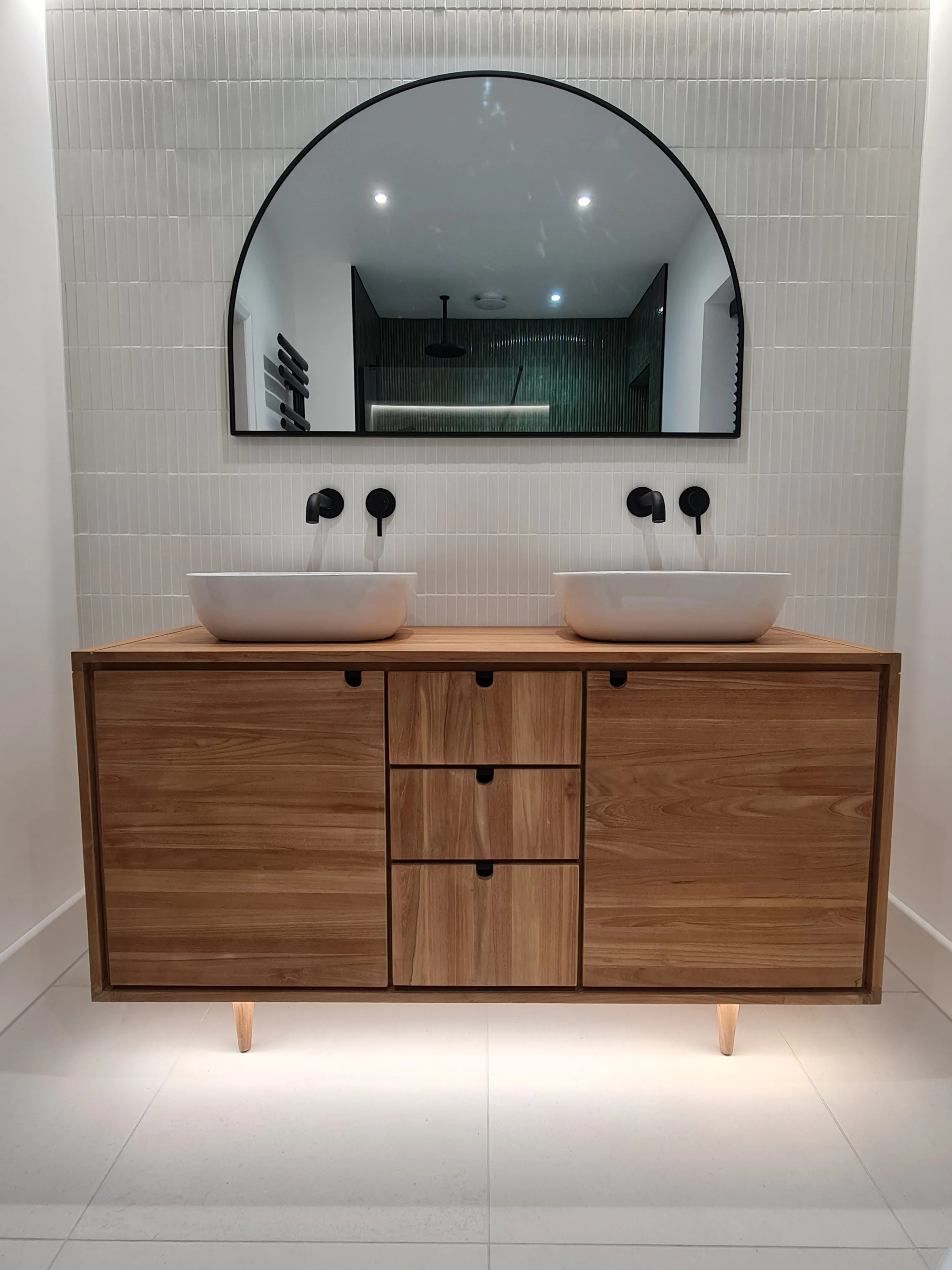 Luxury master bathroom double vanity with wooden cabinets and matte black fixtures installed in a Devon home by Sands & Vossen.