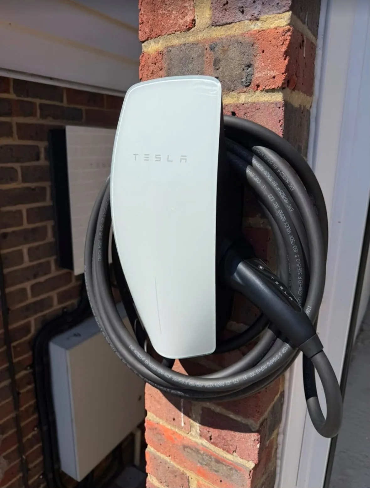 Domestic Tesla EV charger installation on an external brick wall by Sussex Brown Sparks