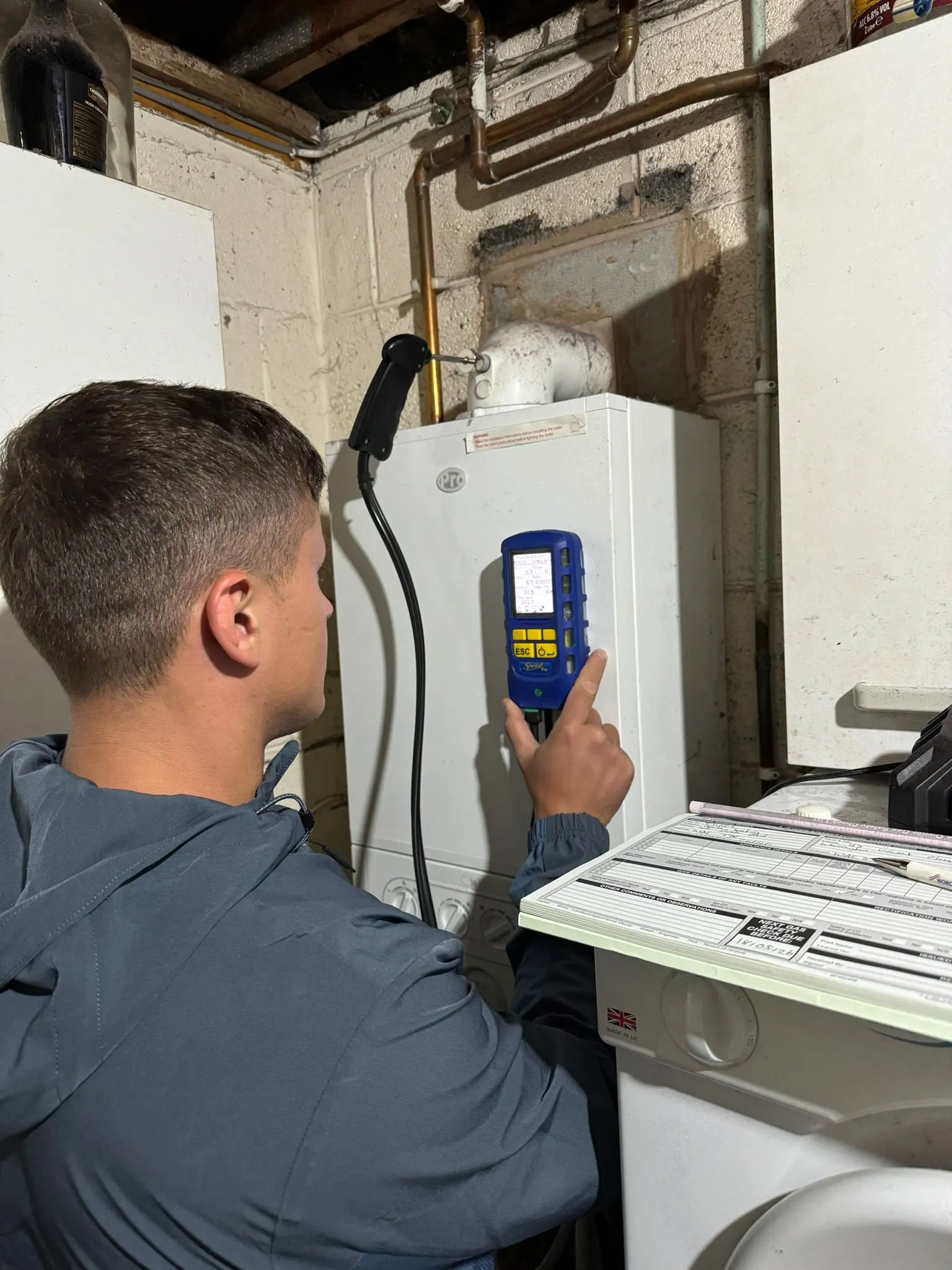 A heating engineer conducting a boiler service and gas safety check in a residential property.