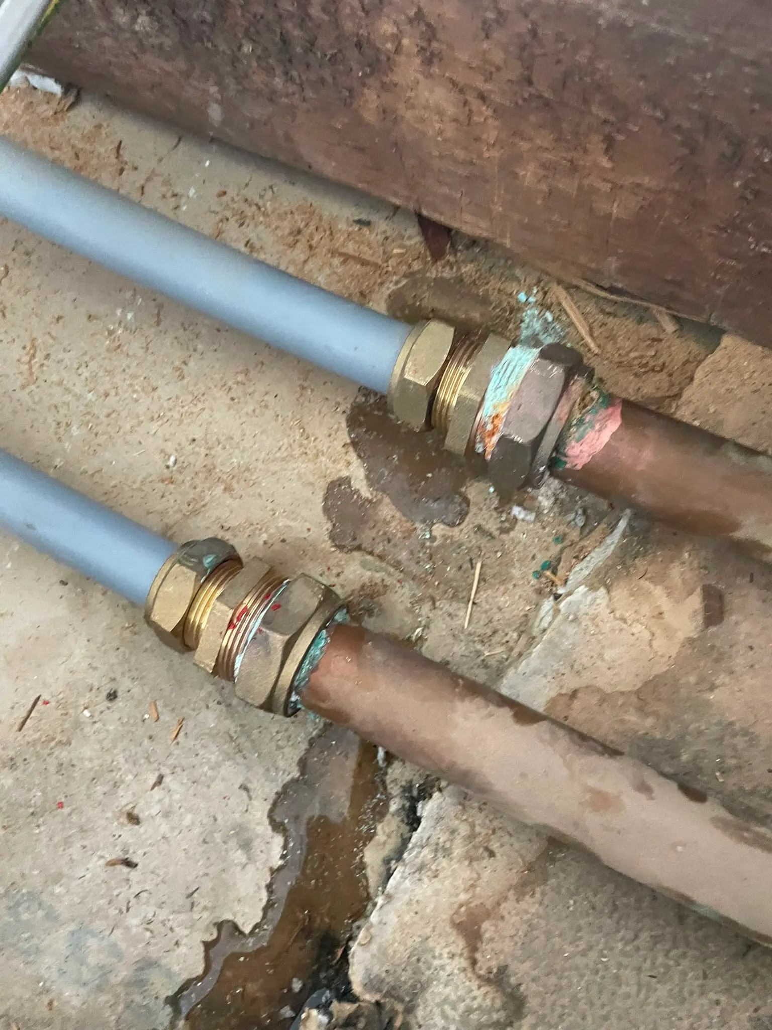 Close-up of a leaking plumbing joint with water dripping onto a concrete floor