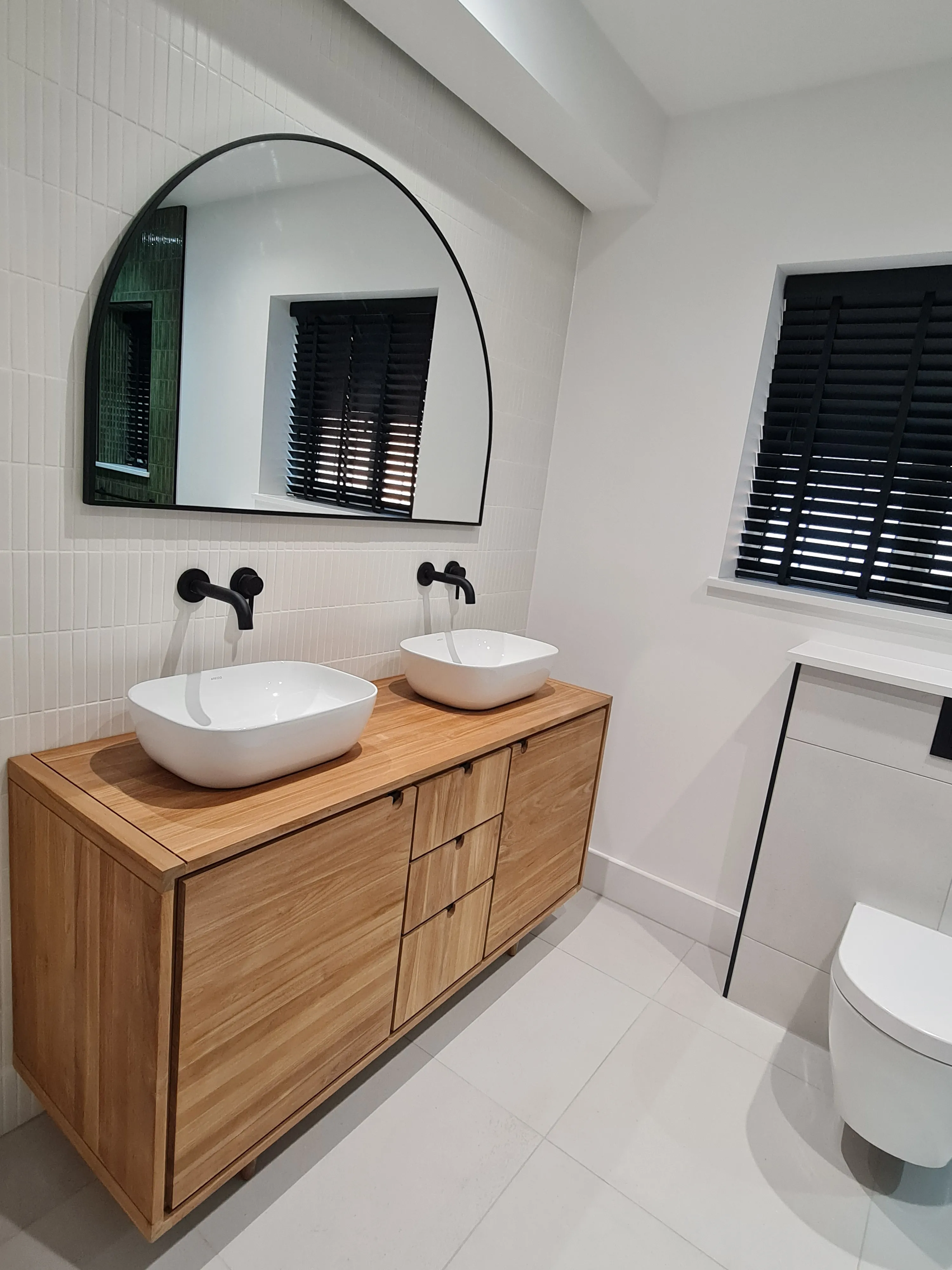 Bespoke luxury master bathroom design and full installation in Plymouth featuring a wooden double vanity and matte black fittings.